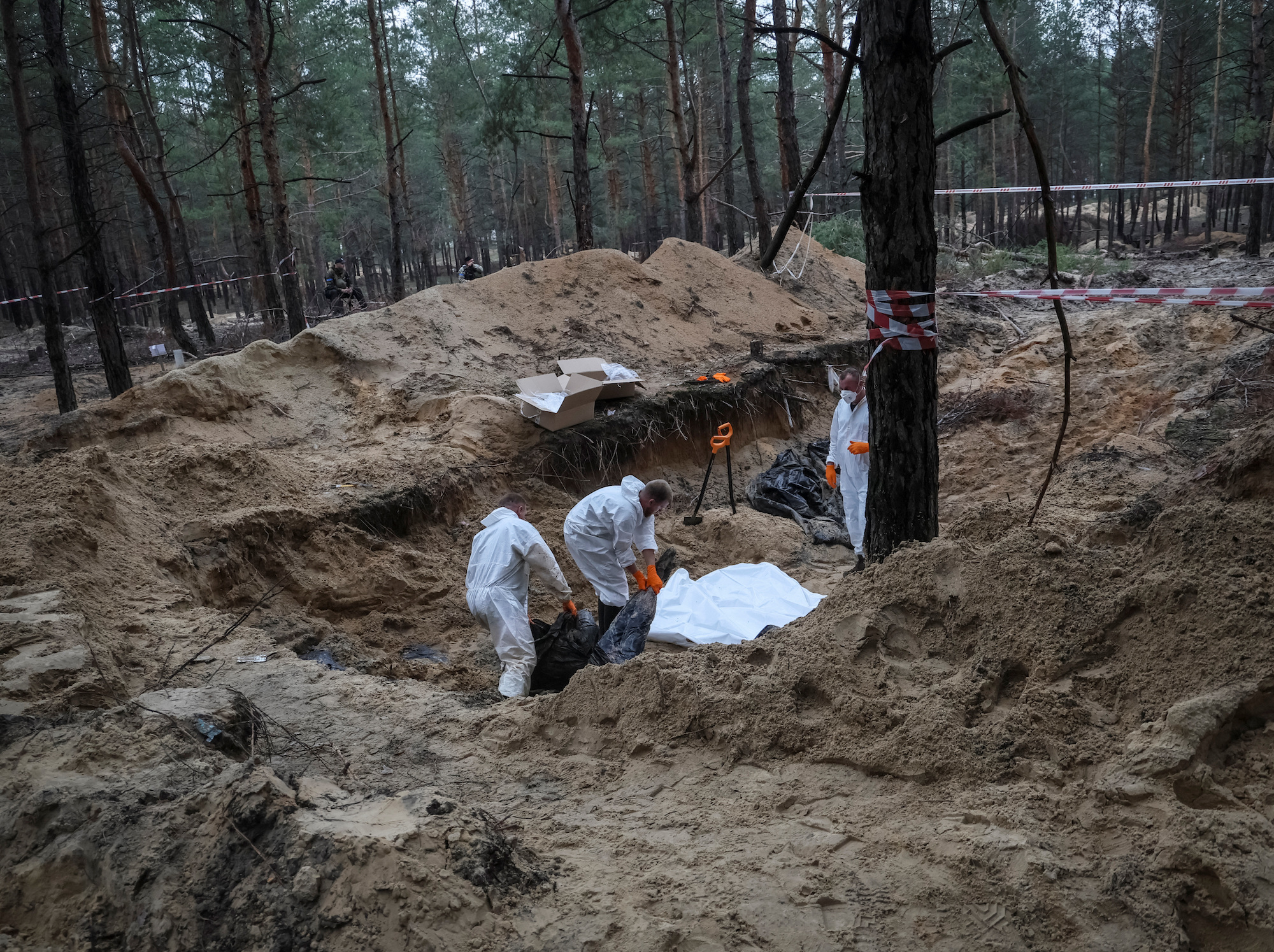 Experts work at a place of mass burial during an exhumation in the town of Izium, Kharkiv region on September 16.