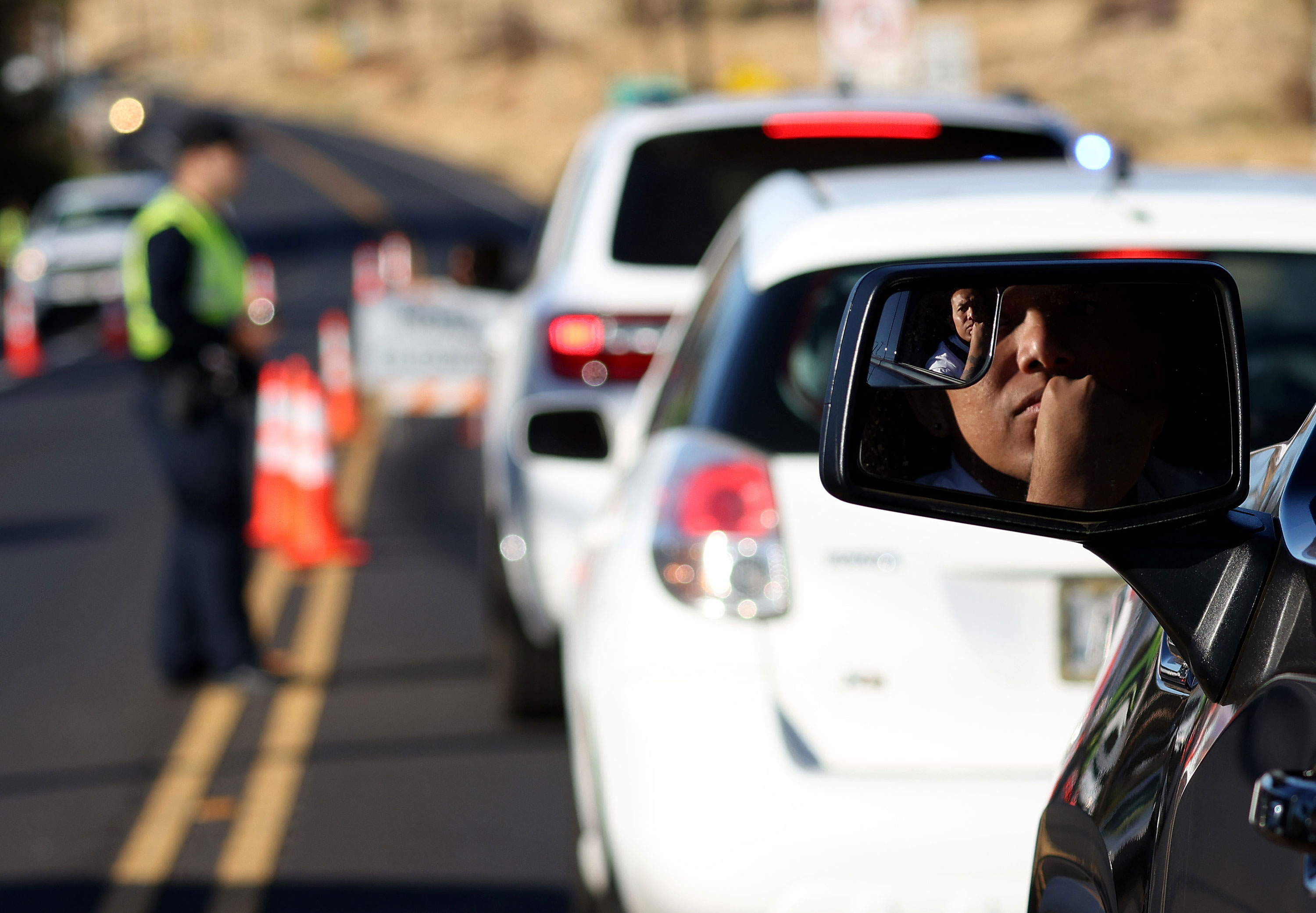 People wait in line at a checkpoint to gain access to Lahaina on Saturday, August 12, in Wailuku, Hawaii. 