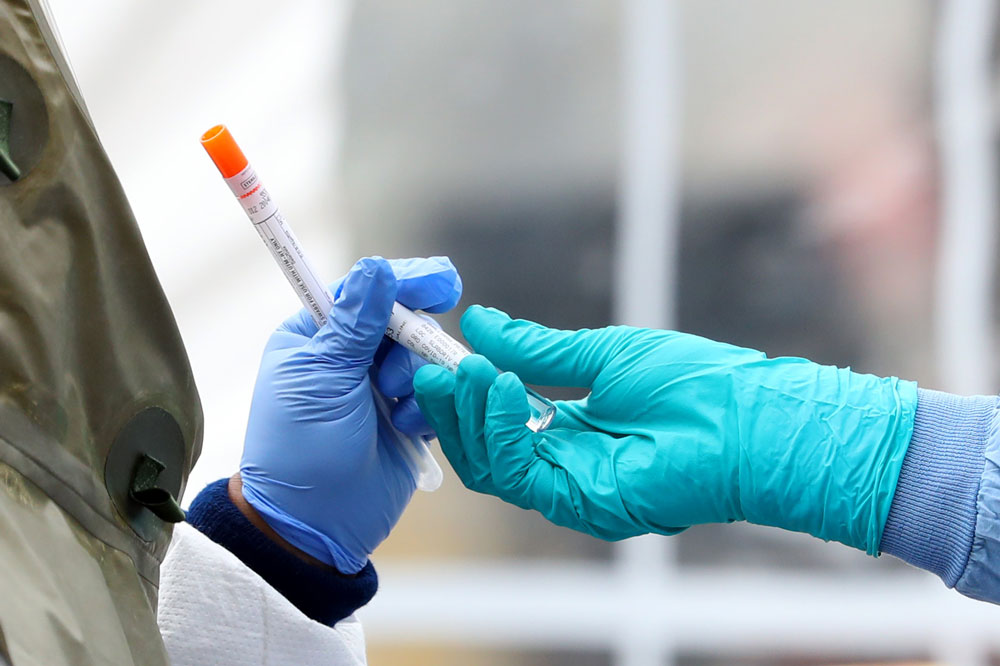 Medical professionals pass each other a coronavirus test at a drive-thru testing site at Cambridge Health Alliance Somerville Hospital on April 28, in Somerville, Massachusetts.
