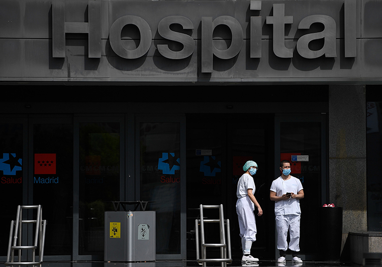 Two health workers stand outside La Paz hospital in Madrid on March 23. 