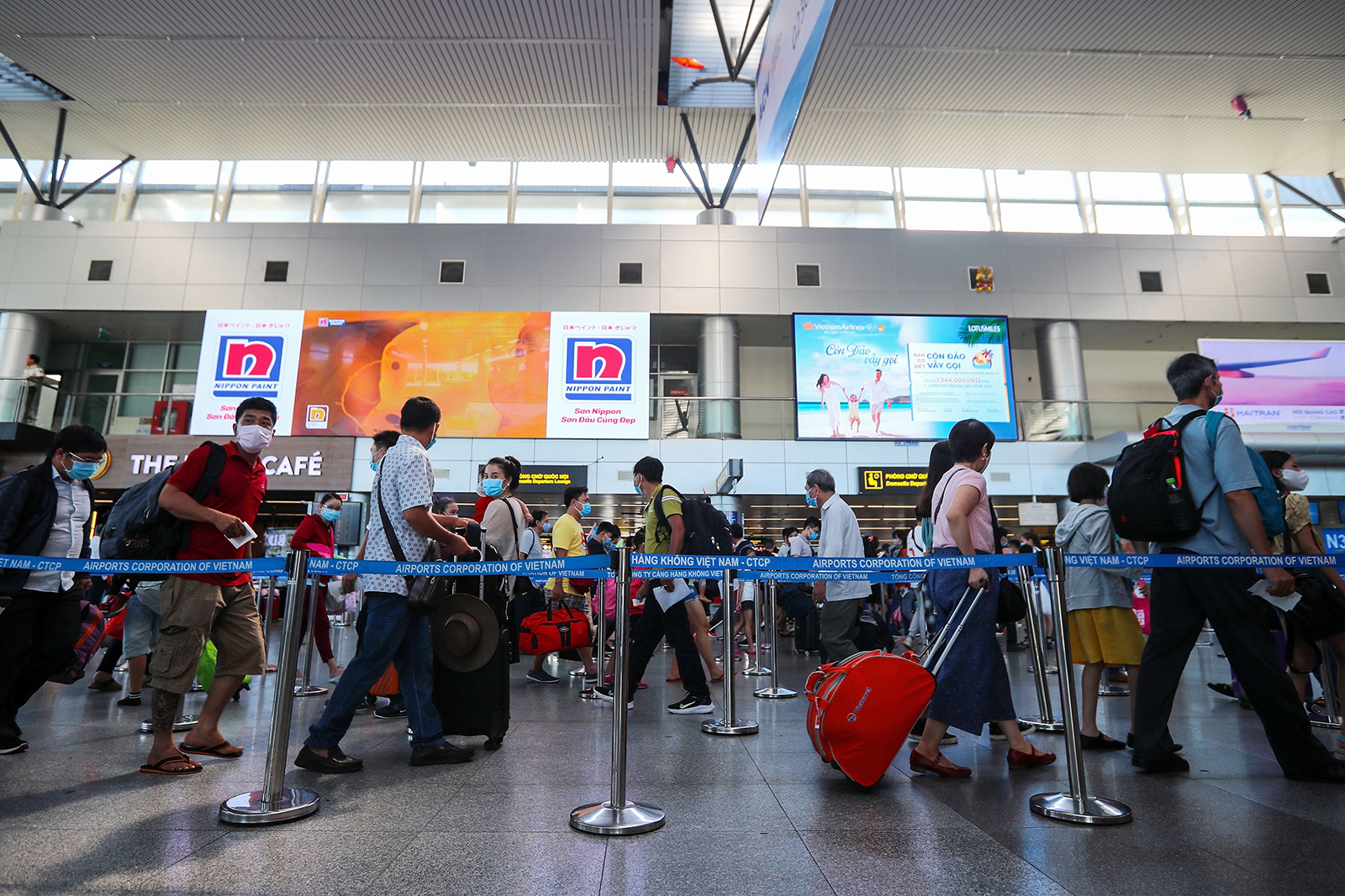 Passengers wearing face masks queue up for check-in at the departures terminal of Da Nang International Airport in Vietnam on July 27.