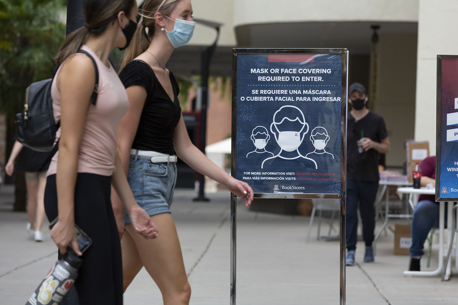 Students pass in front of a sign that reads "Mask Or Face Covering Required To Enter" at the University of Arizona in Tucson on August 24.