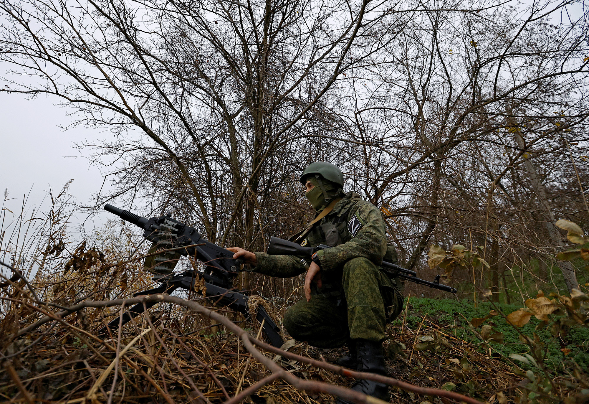A Russian service member sits near an automatic grenade launcher at a combat position on the left bank of the Dnipro river in the Zaporizhzhia region, Ukraine, on November 26.