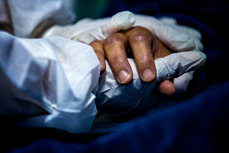 A health worker wearing personal protective equipment holds the hand of a patient at the Doctor Ernesto Che Guevara Public Hospital where patients infected with the novel coronavirus, COVID-19, are being treated on April 30, 2021 in Maricá, Brazil. 