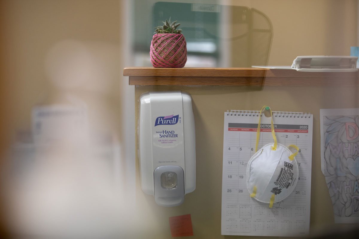 An N95 mask hangs next to a hand sanitizer dispenser on a reception's desk at a clinic in Lansing, Michigan on October 18, 2020.