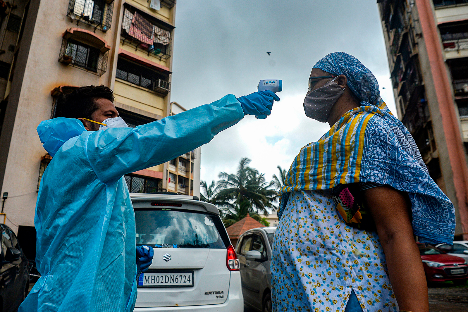 A health worker, left, takes the temperature of a resident during a door-to-door medical screening drive in Mumbai on Monday, July 20.