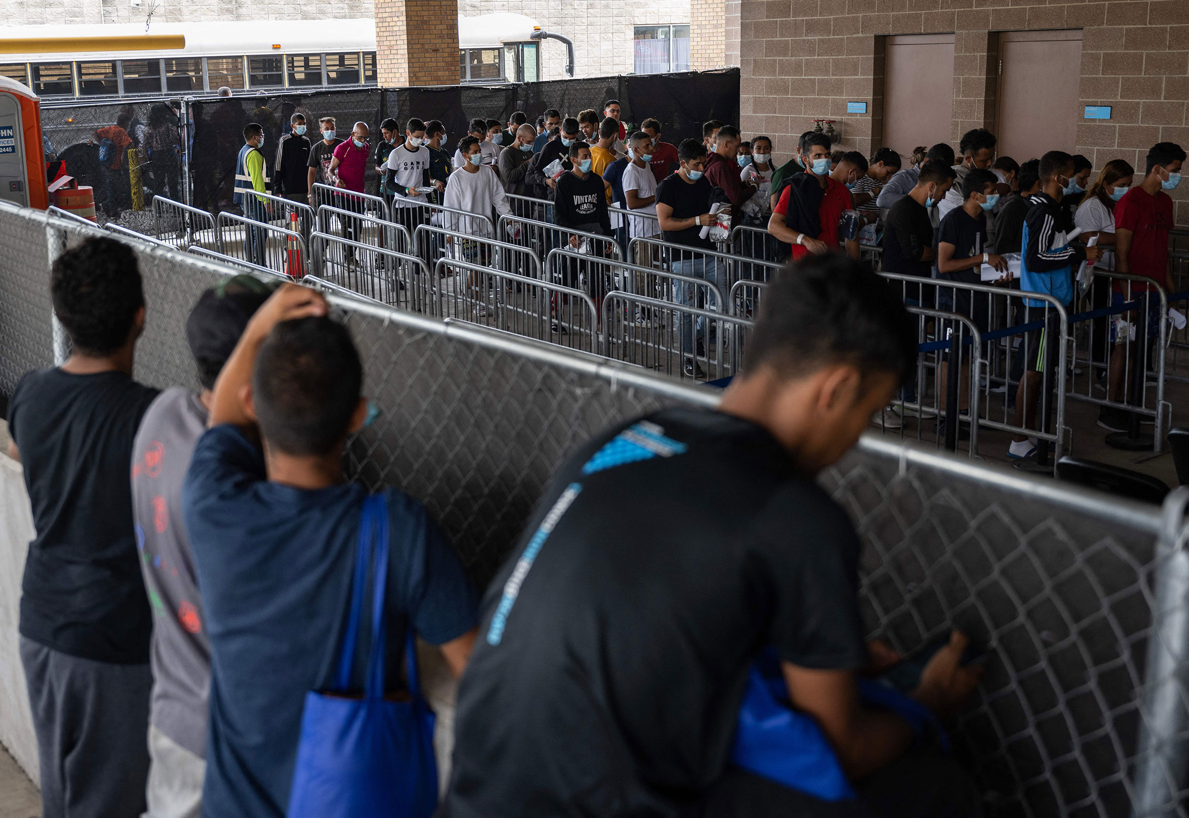 Migrants look over a fence as they try to locate family members and friends that arrived at a processing center in Brownsville, Texas, on May 11. 