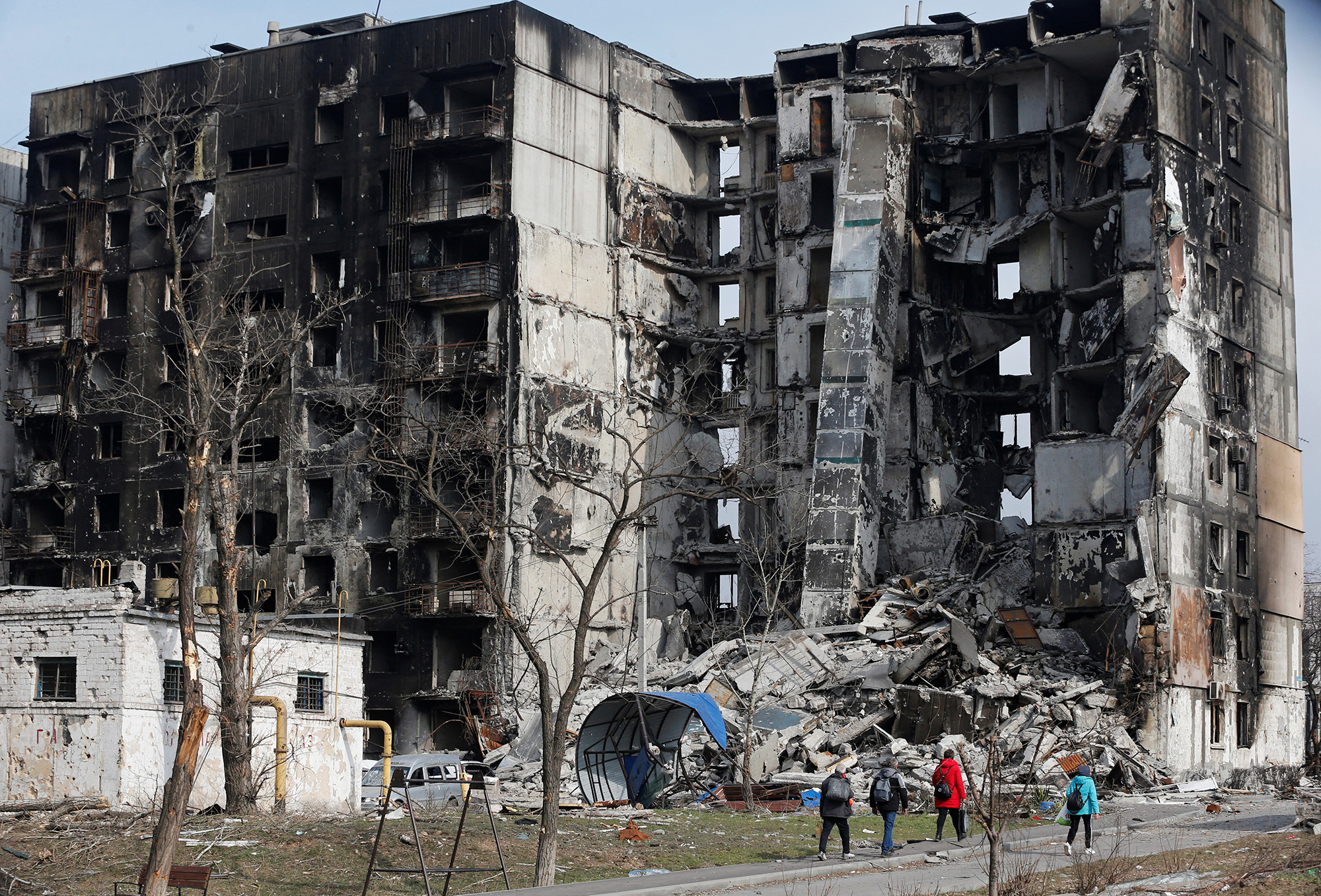 Local residents walk near a destroyed apartment building in the besieged southern port city of Mariupol, Ukraine, on March 30.