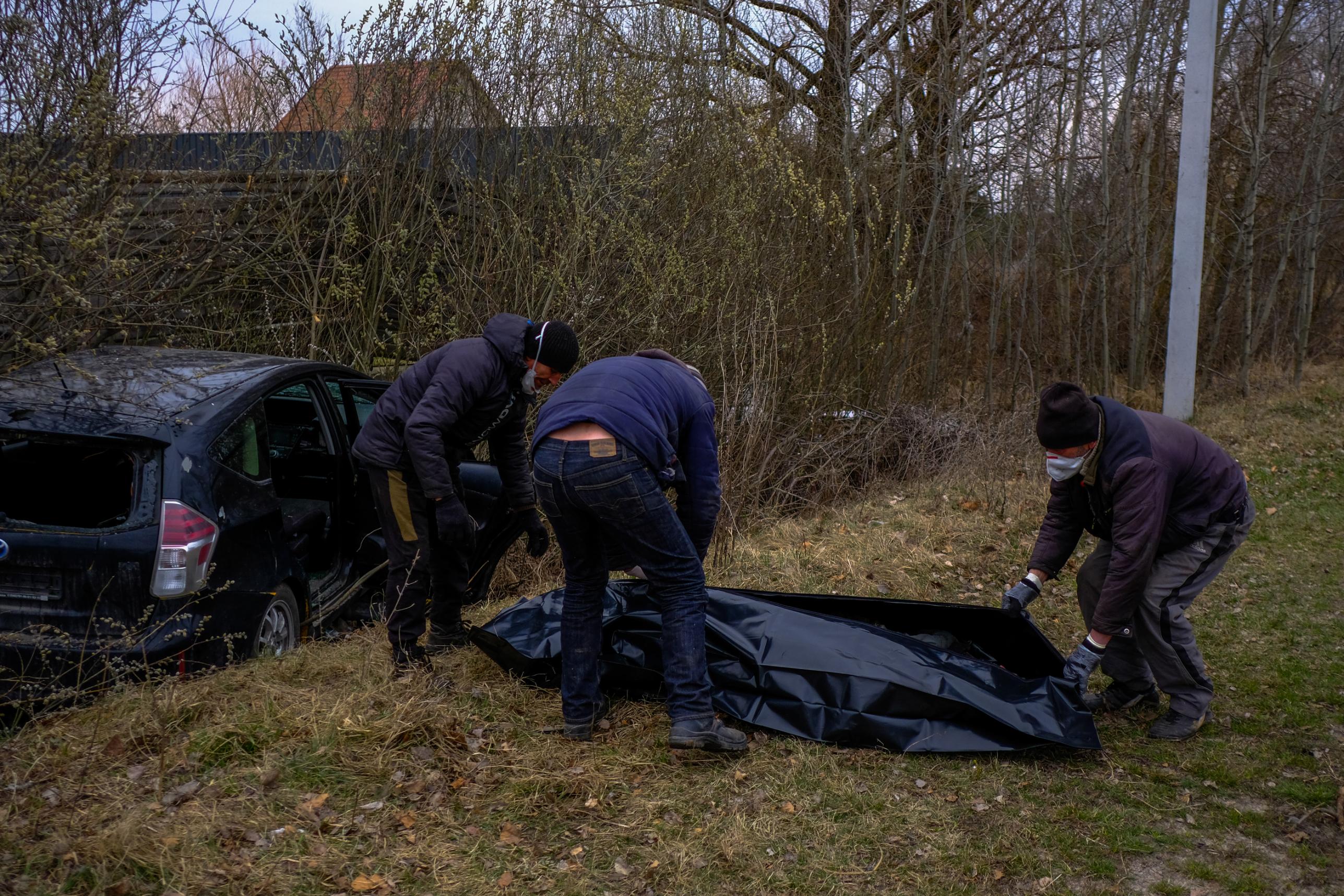 Volunteers collect the body of a man who was shot while driving his car in Borodianka, Ukraine.