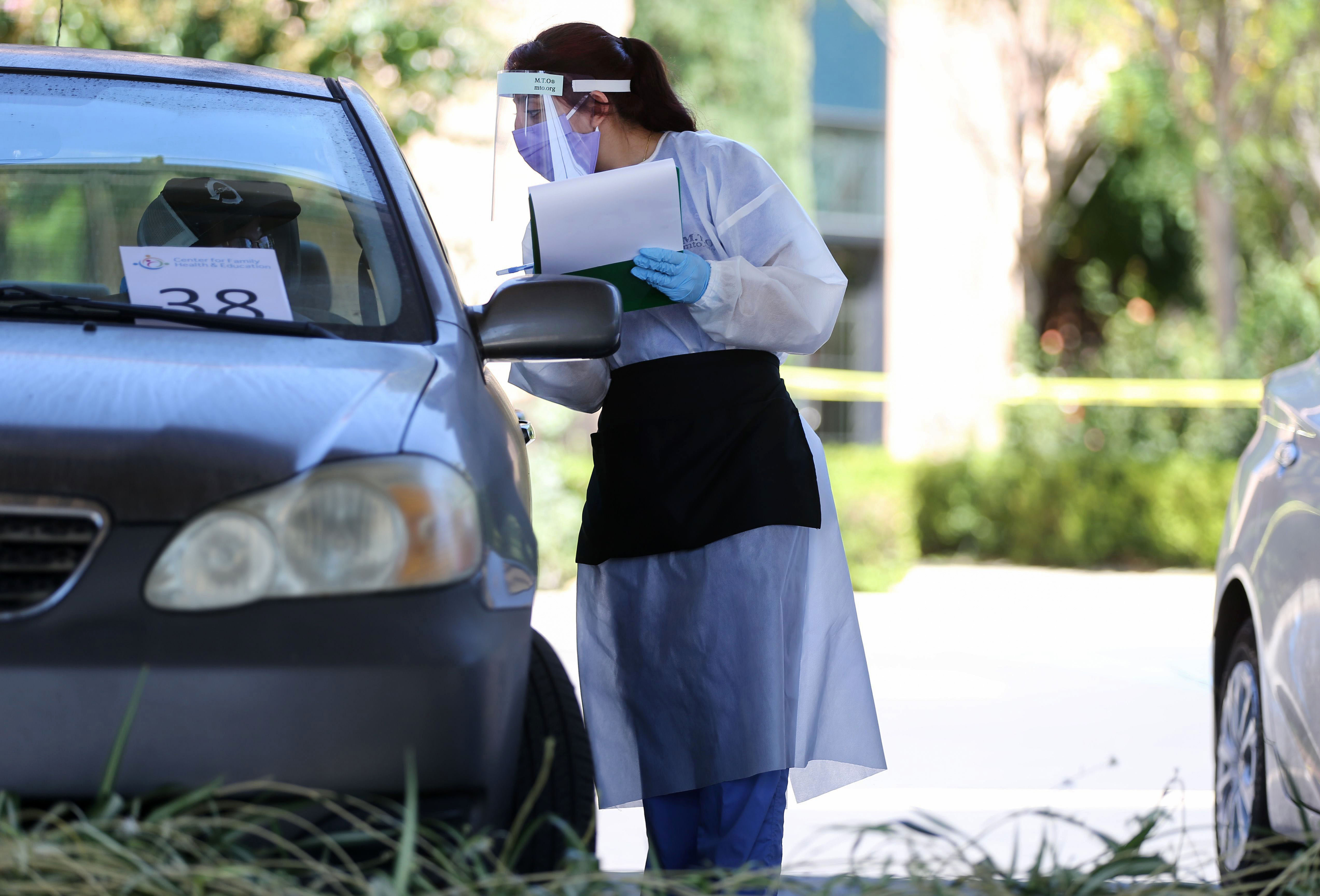 A health care worker in Los Angeles takes someone's information at a drive-in Covid-19 testing center on August 11.