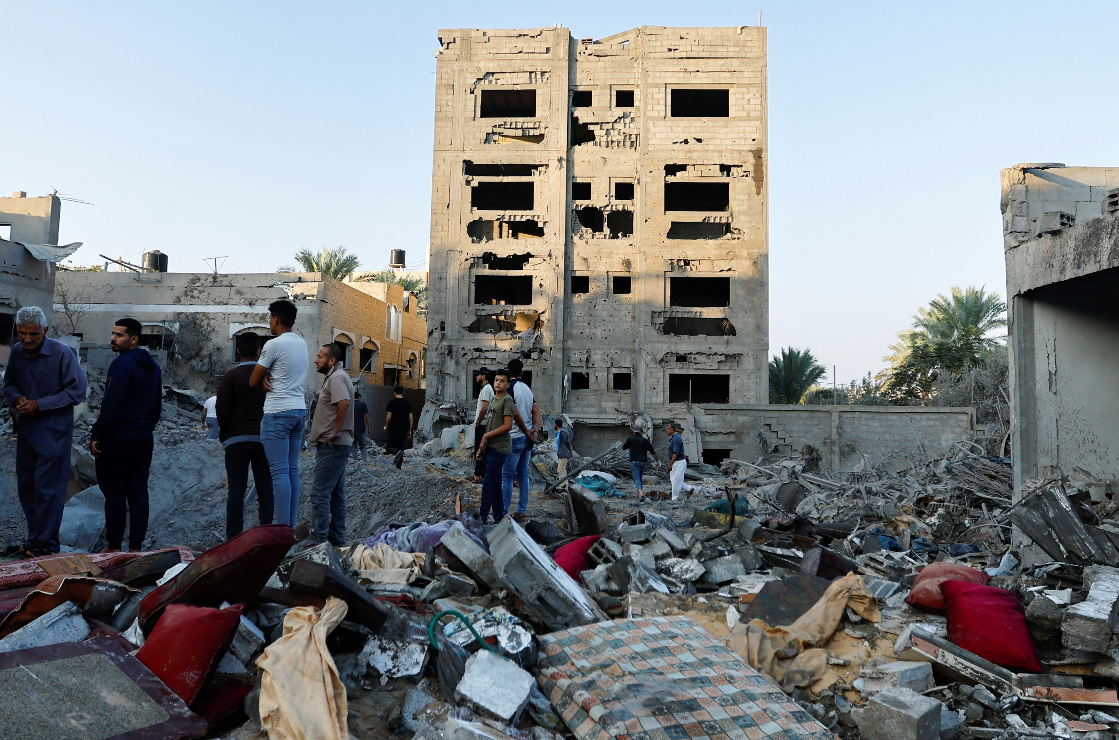 Palestinians look at the destruction of a house in the aftermath of a strike amid the conflict with Israel in Khan Younis, southern Gaza, on October 12, 2023.