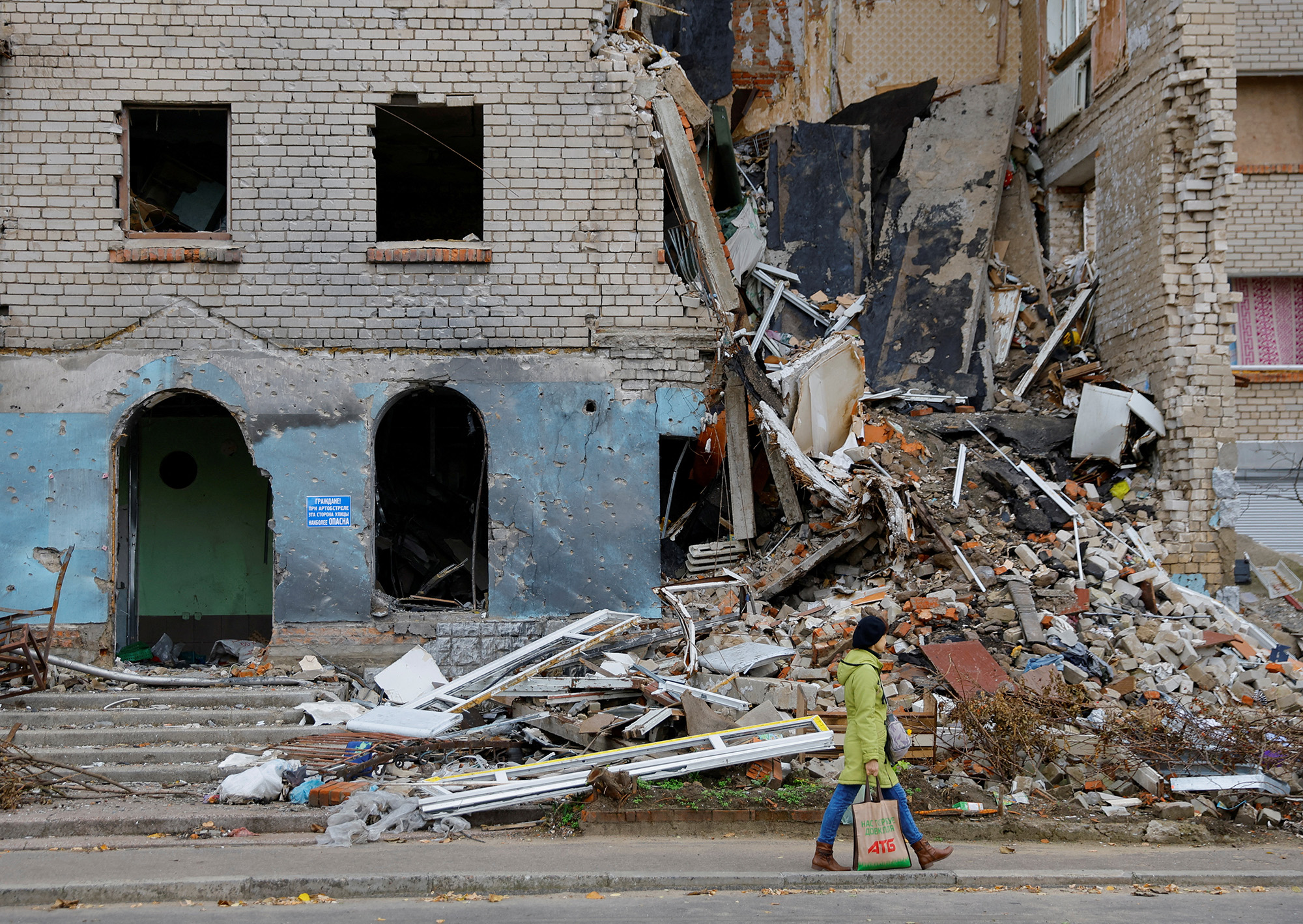 A woman walks past a damaged building in the town of Nova Kakhovka, Ukraine, on October 30.