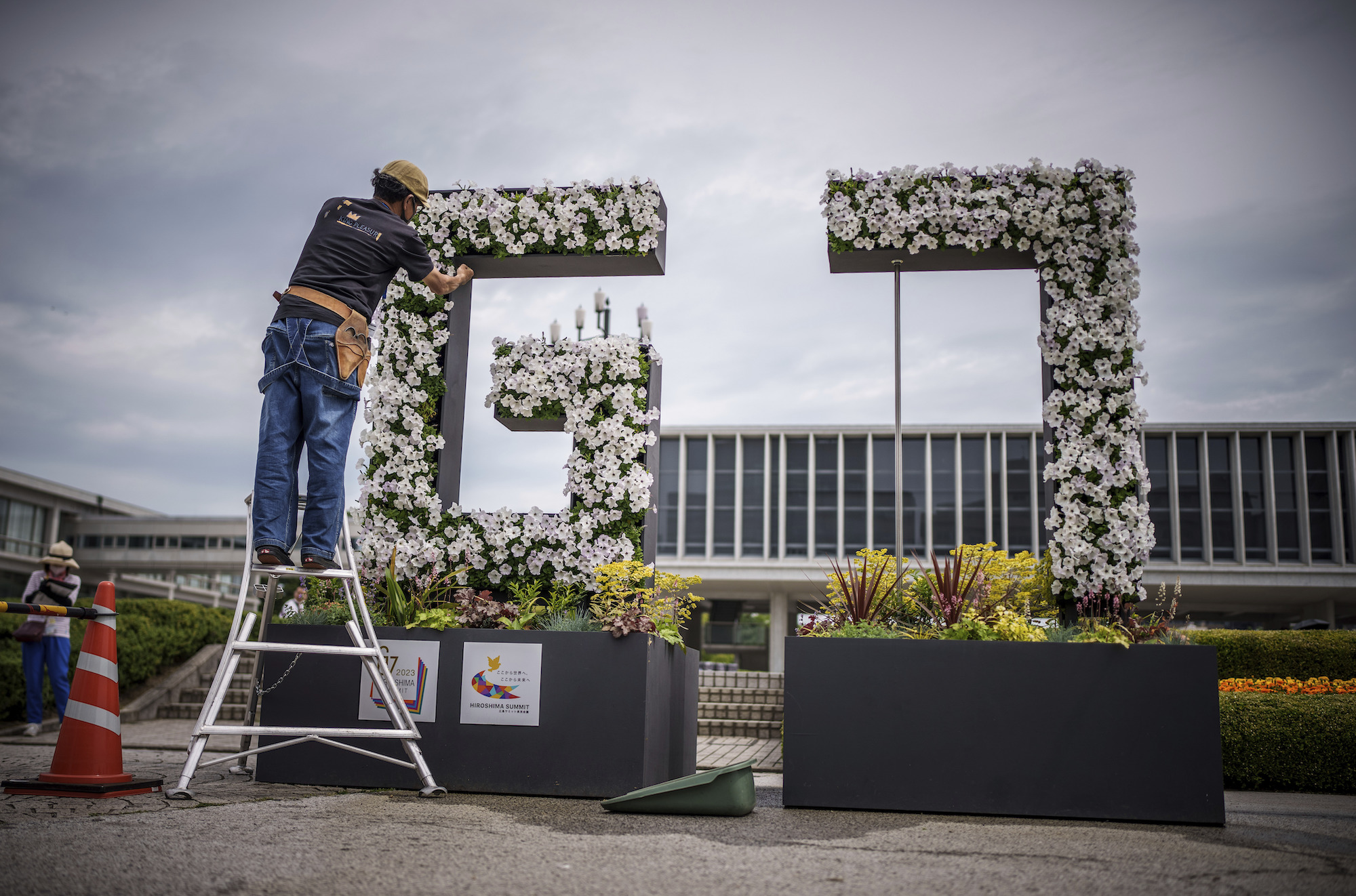 A gardener works on a G7 logo made of flowers with Genbaku Dome in the background in Hiroshima Peace Memorial Park on Thursday.