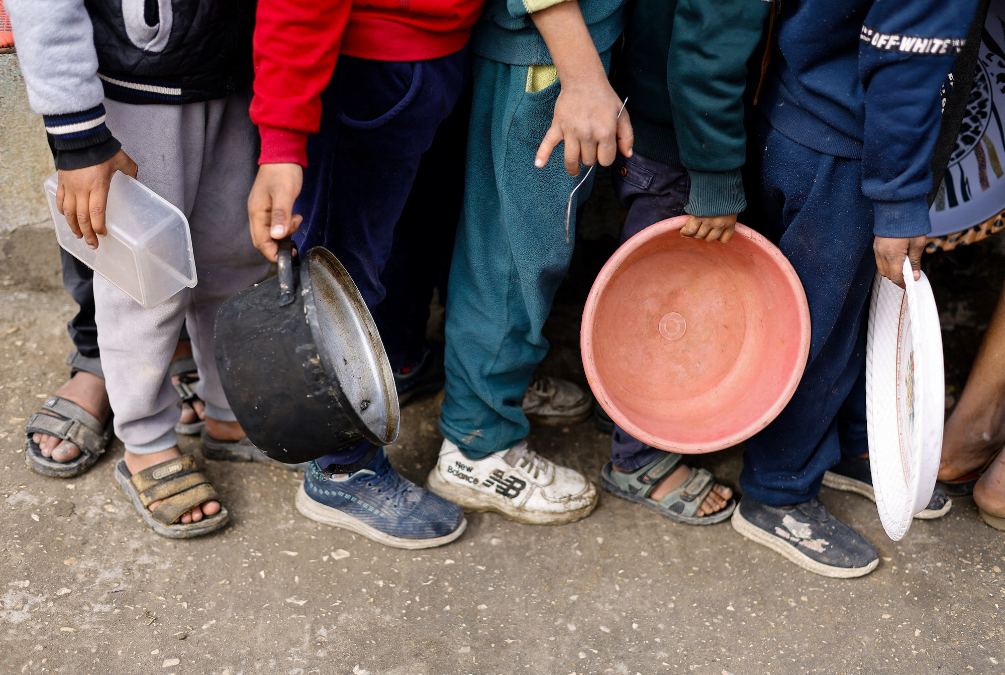 Palestinian children hold empty containers as they wait to receive food in Rafah, Gaza, on January 17.