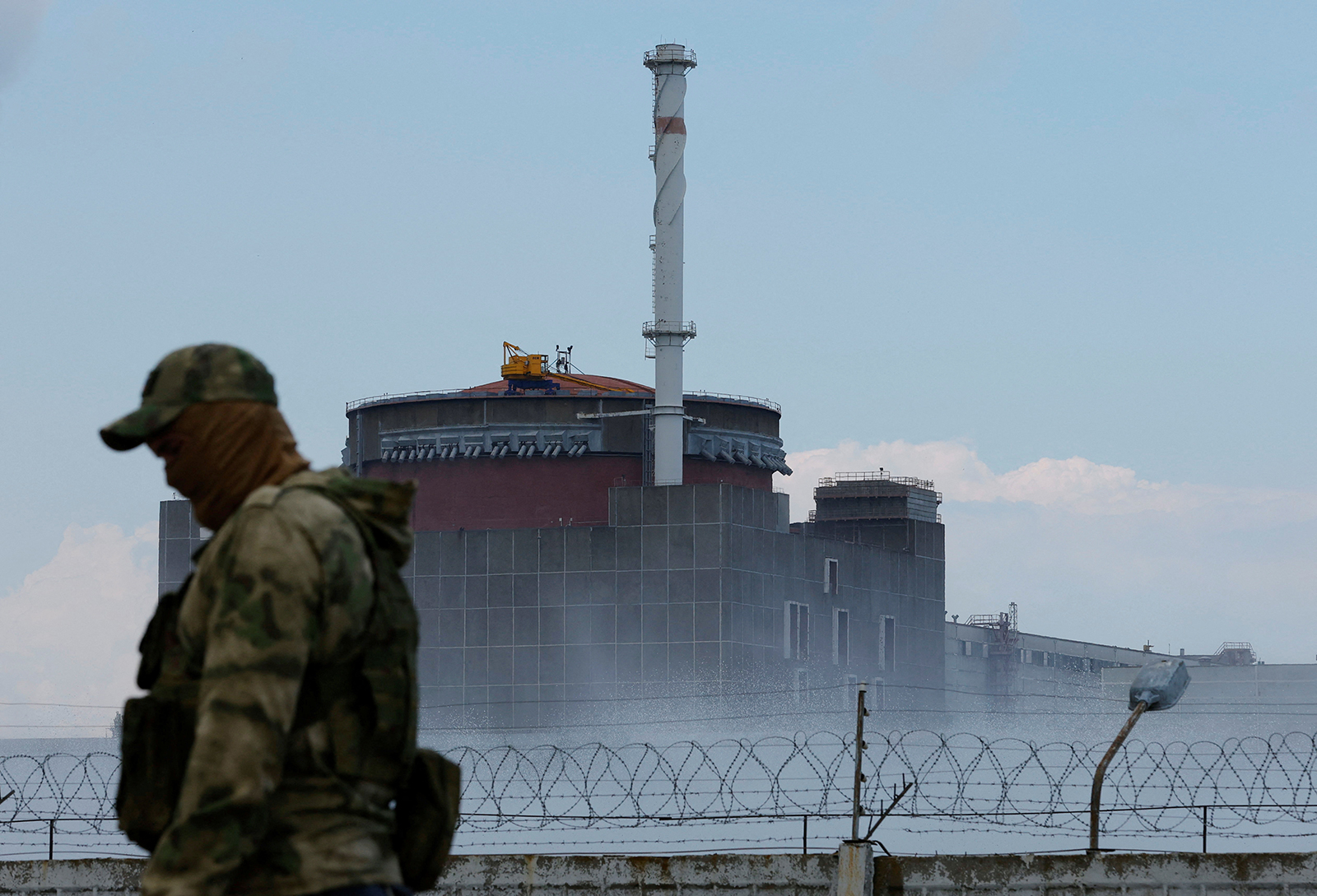 Un soldado hace guardia con su uniforme y una bandera rusa cerca de la planta de energía nuclear de Zaporizhia, en las afueras de la ciudad de Enerhodar, controlada por Rusia, en la región ucraniana de Zaporizhia, el 4 de agosto.