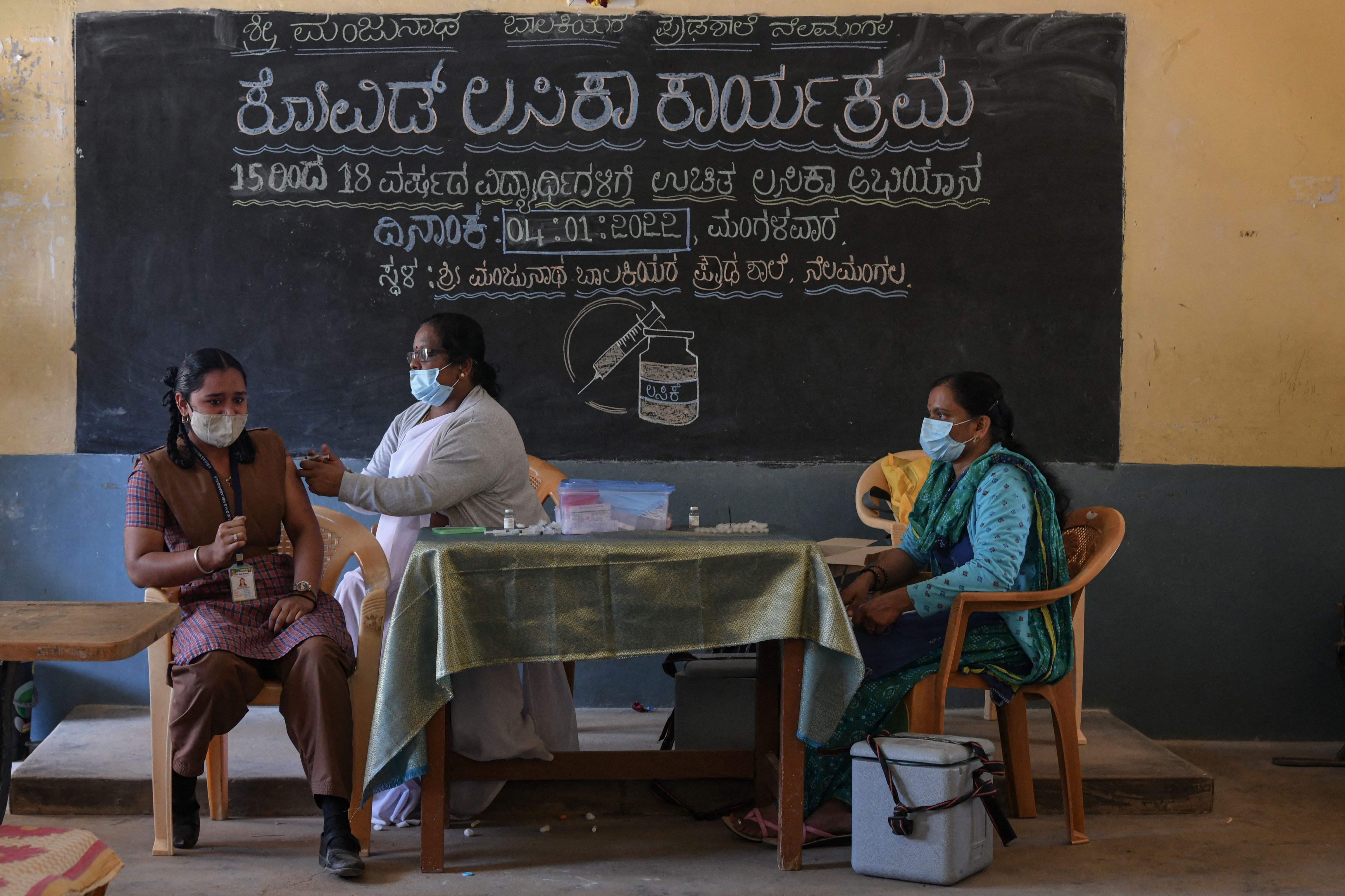 A health worker inoculates a student with a dose of the Covaxin vaccine against the Covid-19 coronavirus during a vaccination drive for youths of the 15-18 group age at a Government High School in Bangalore on January 4, 2022. 