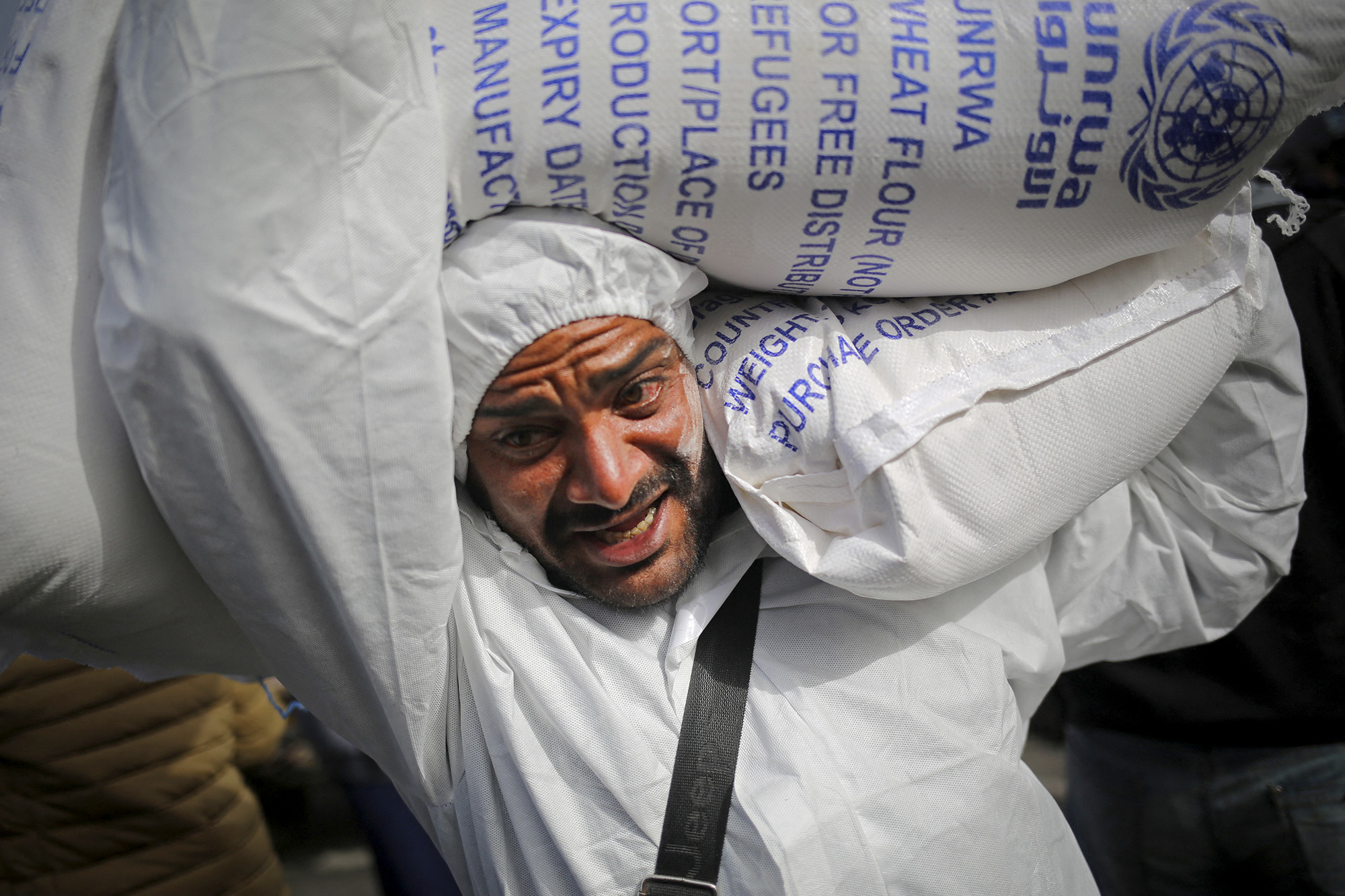 A Palestinian man carries sacks of humanitarian aid at the distribution center of the United Nations Relief and Works Agency for Palestine Refugees (UNRWA) in Rafah, Gaza, on March 3.