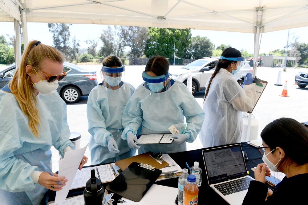 Workers wearing personal protective equipment perform drive-up Covid-19 tests at Mend Urgent Care testing site on May 13 in Los Angeles, California.