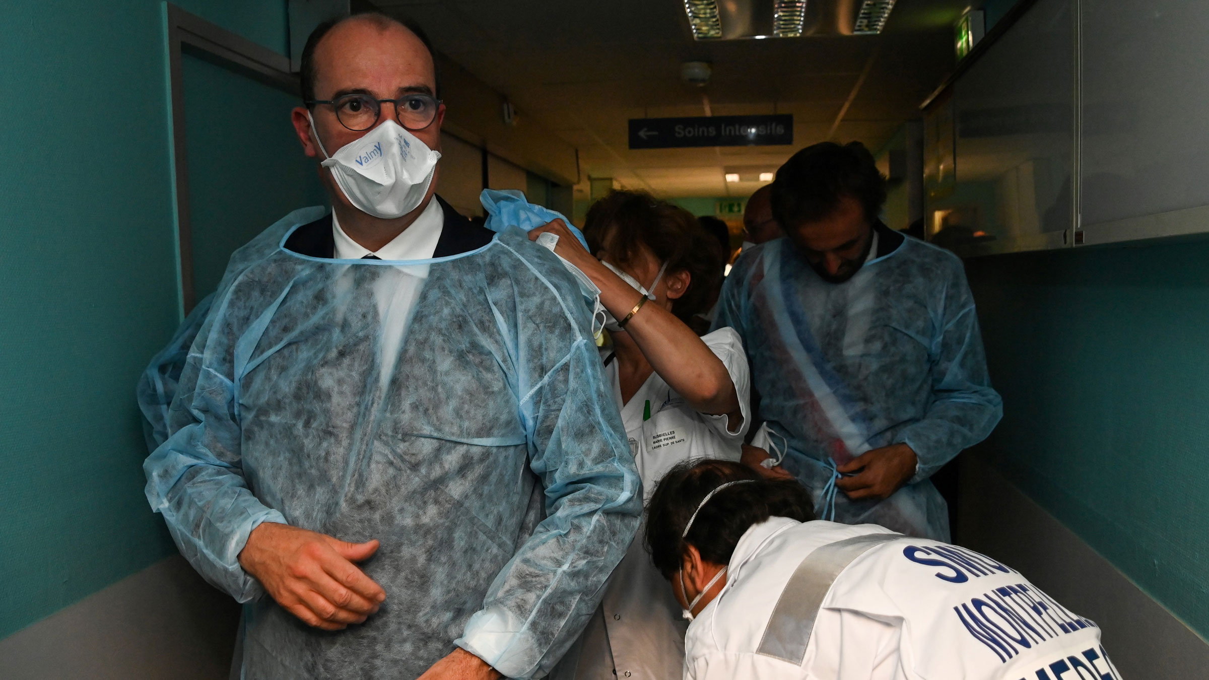 French Prime Minister Jean Castex, left, is helped into a protective suit before visiting a hospital in Montpellier, France, on Tuesday.