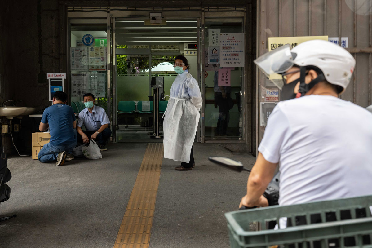 A worker wearing a protective mask and goggles stands in front of a hospital entrance in Taipei, Taiwan, on May 17.