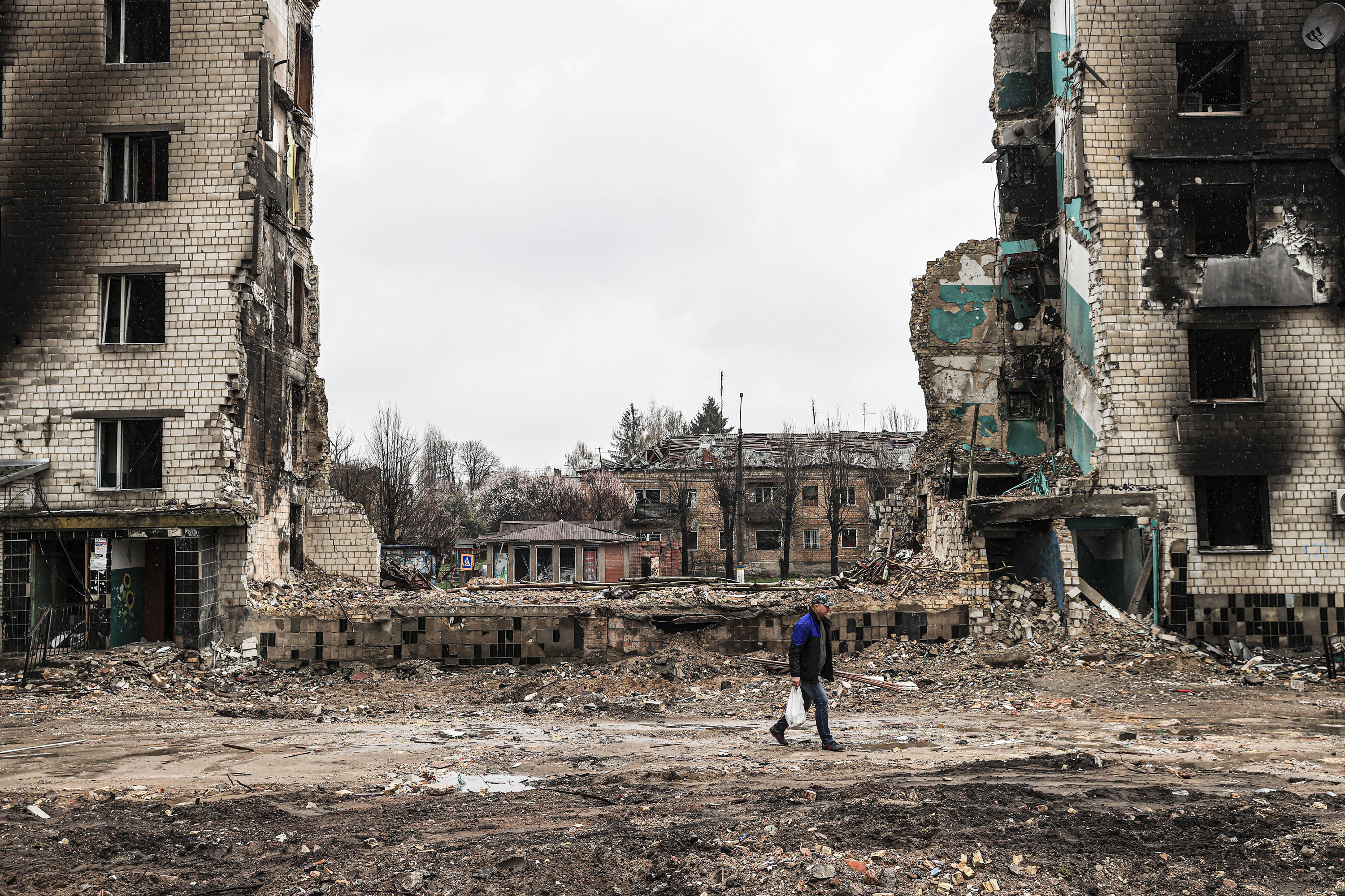 A Ukrainian person walks through the ruins of damaged buildings in Borodianka, on April 22, 2022.