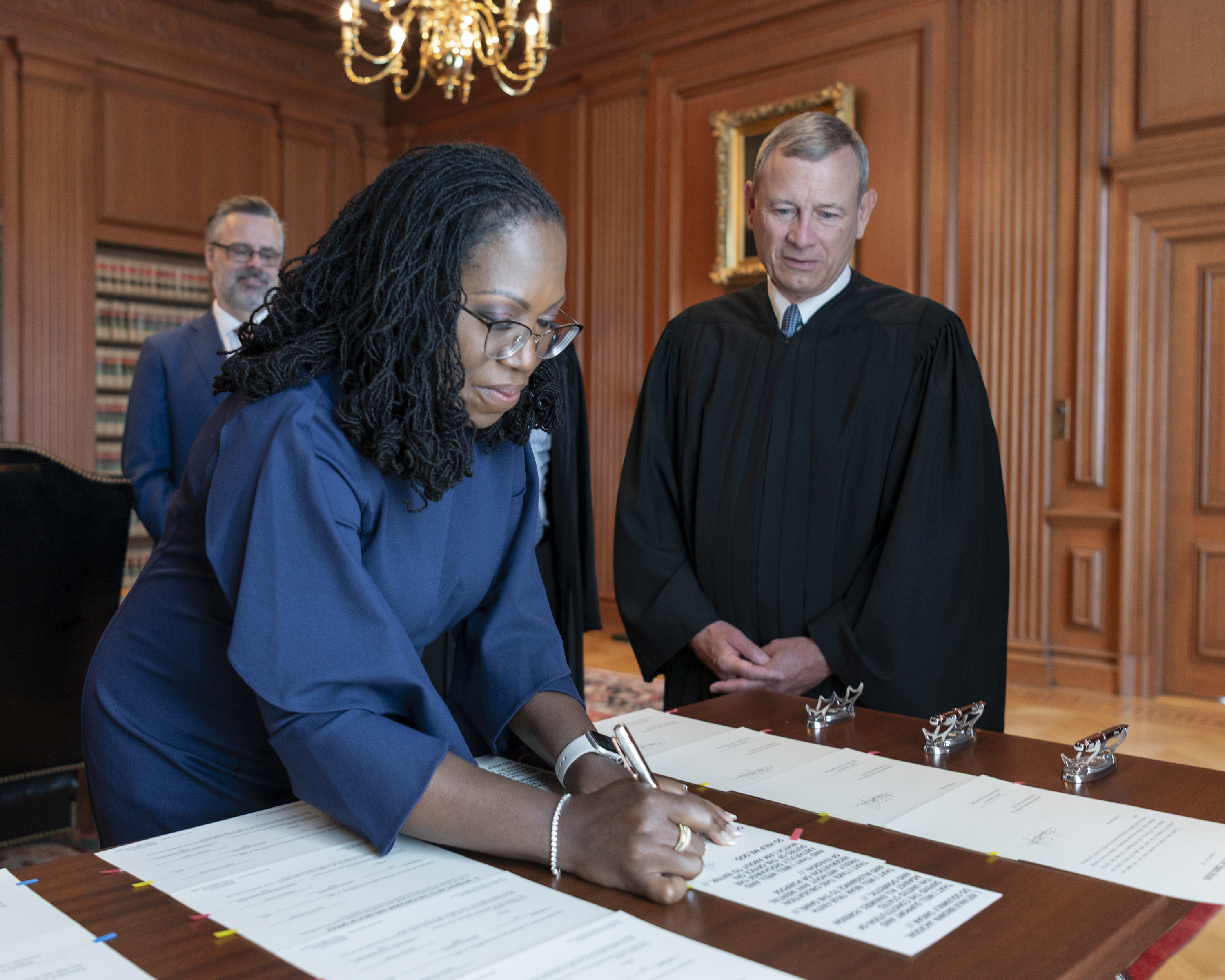 Chief Justice John G. Roberts Jr. looks on as Justice Ketanji Brown Jackson signs the Oaths of Office in the Justices' Conference Room at the Supreme Court on June 30 in Washington, DC.