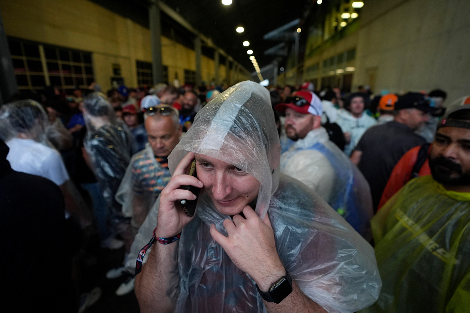 A race fan makes a phone call while trying to stay dry during a weather advisory before the Indianapolis 500 auto race at Indianapolis Motor Speedway, in Indianapolis, Indiana on May 26.