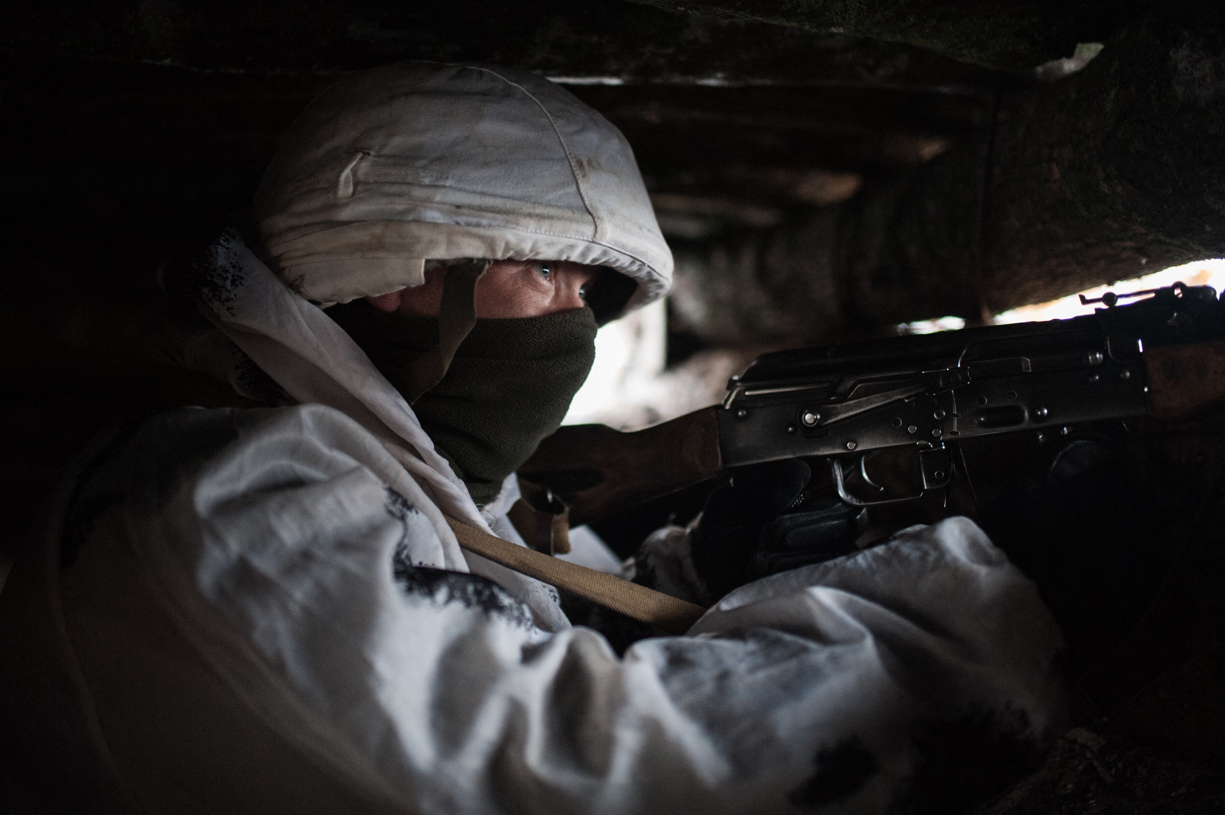 Pro-Russian Serviceman with a machine gun observing the front line in the dugout of the people's militia of the Luhansk People's Republic, Donbas, Ukraine on February 3