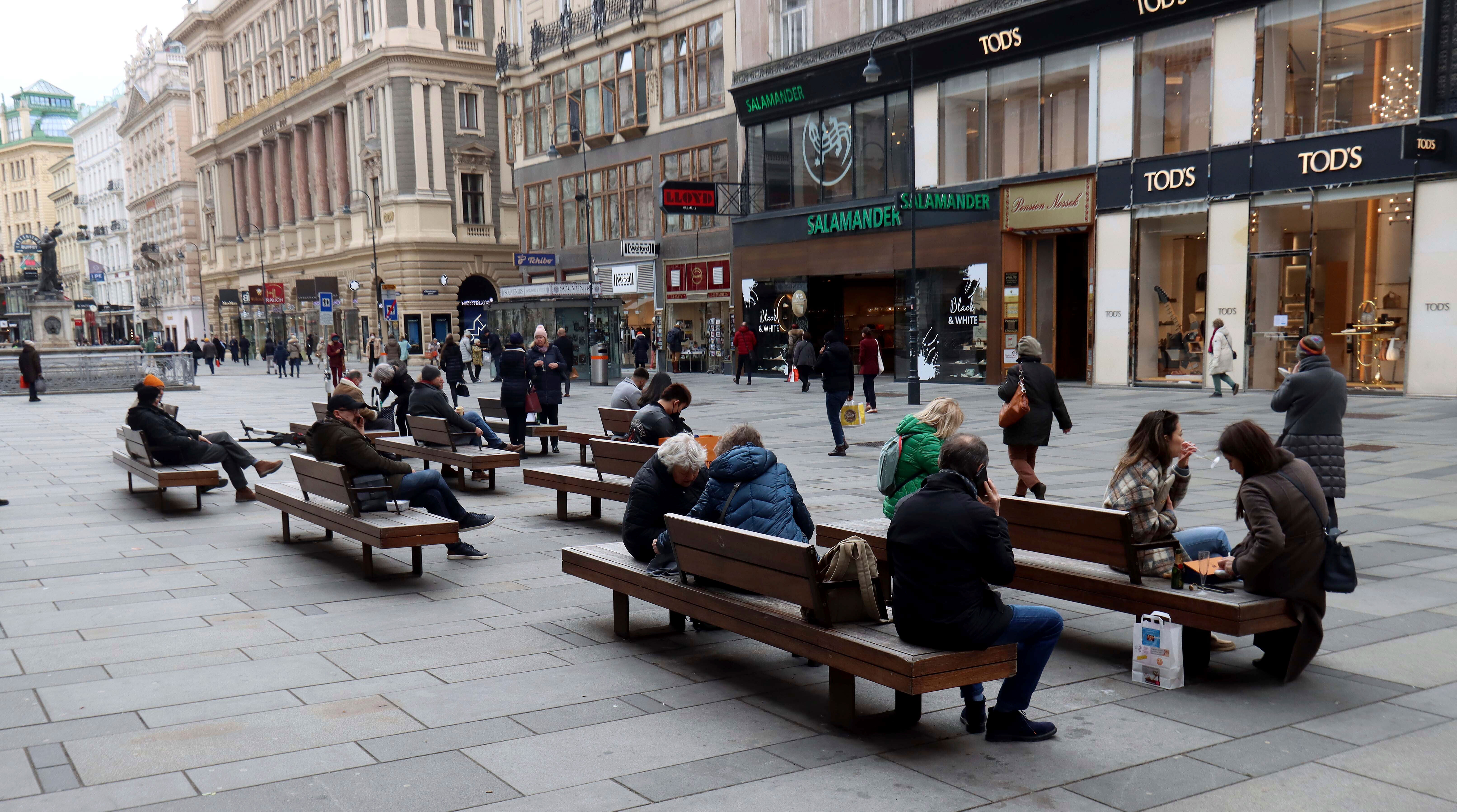 People sit on benches in downtown Vienna, Austria, on March 22.