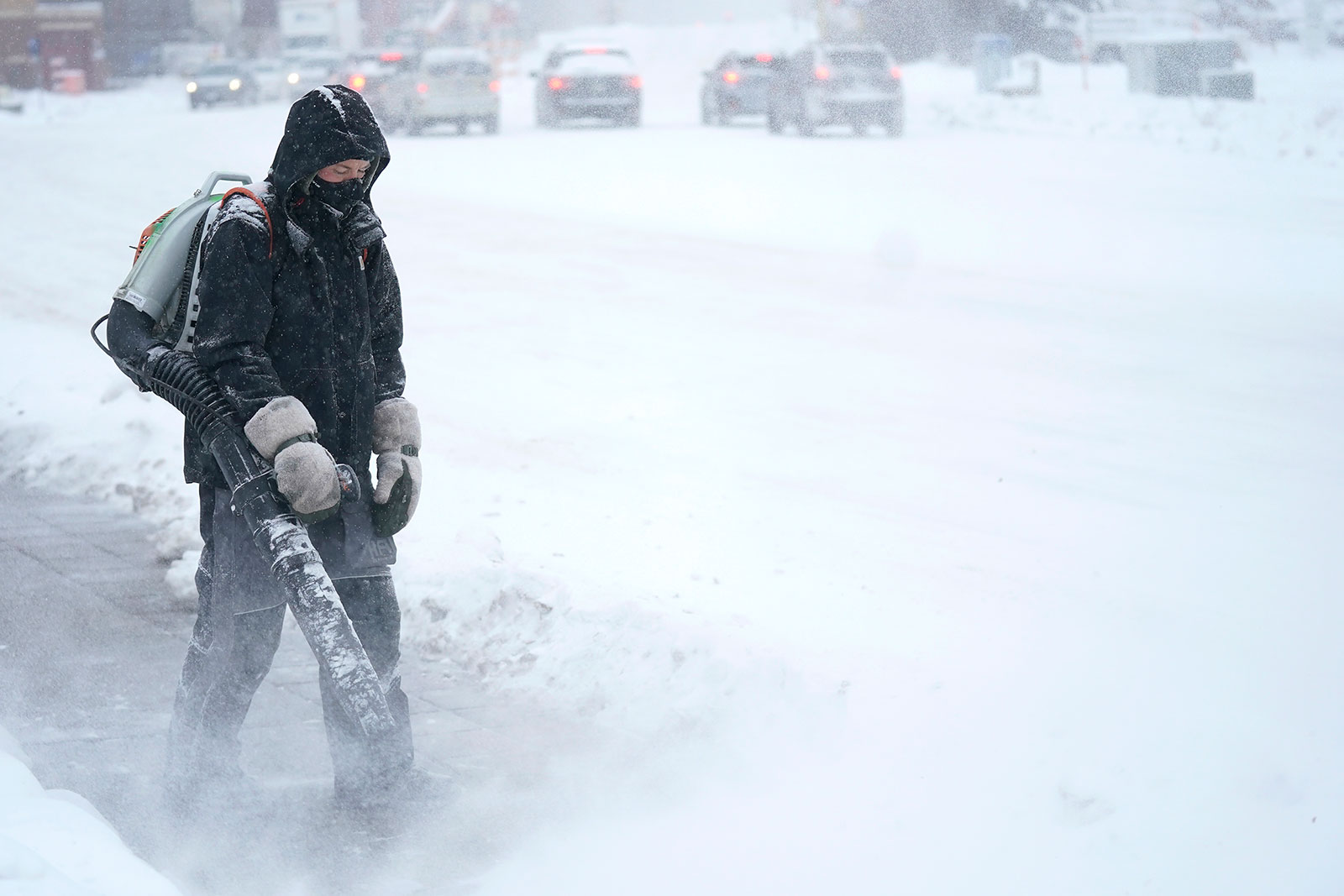A man blows snow off a sidewalk on December 21 in Minneapolis. 