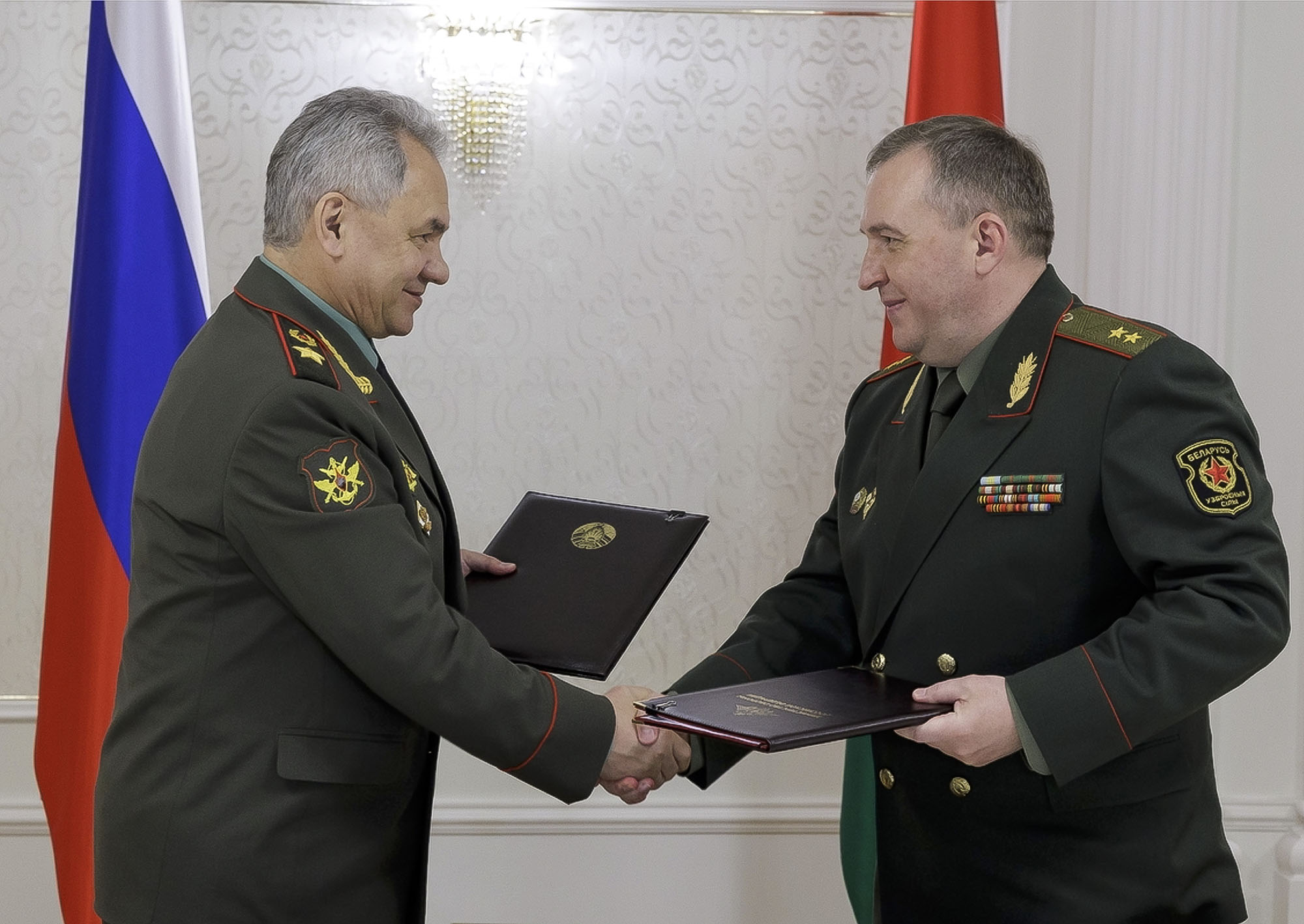 Russian Defense Minister Sergei Shoigu, left, and Belarusian Defense Minister Viktor Khrenin exchange documents during a meeting after a session of the Council of Defense Ministers of the Collective Security Treaty Organization (CSTO) in Minsk, Belarus, on May 25.