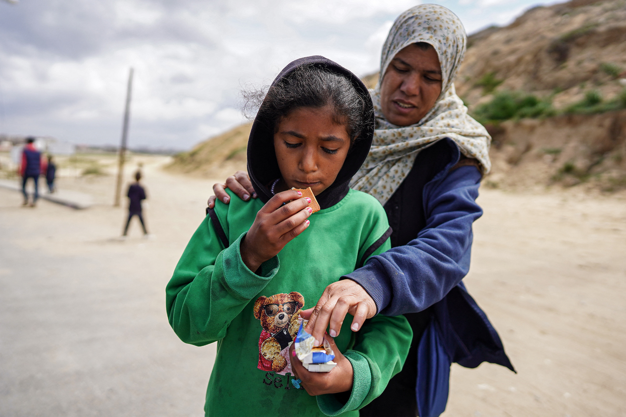 A girl and woman eat biscuits as they evacuate from Gaza City on March 25.
