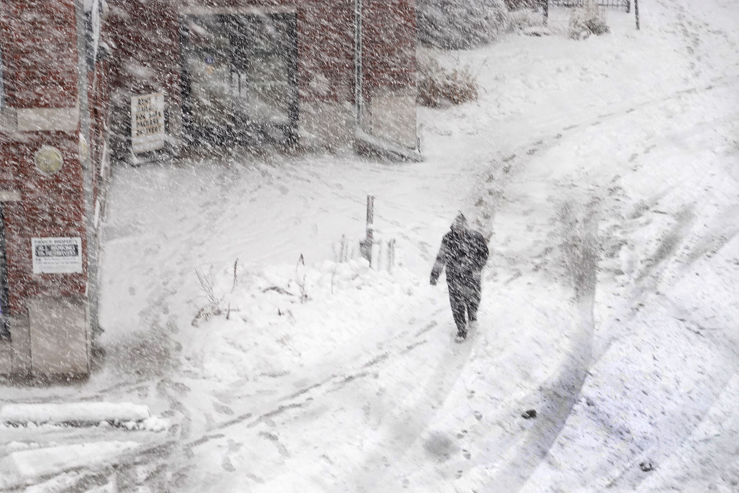 A pedestrian navigates a snow-covered sidewalk on January 9, in Iowa City, Iowa.