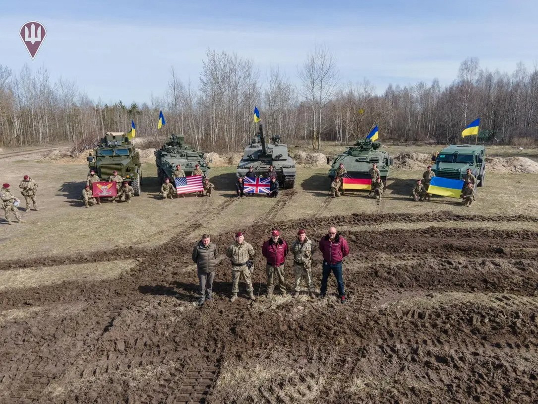 Ukraine's Defense Minister Oleksii Reznikov and Commander of the Air Assault Forces Maksym Myrhorodskyi pose for a picture in front of a British Challenger 2 main battle tank, US Stryker and Cougar armoured personnel carriers and German Marder infantry fighting vehicle, in an unknown location in Ukraine, in this handout picture released on March 27.