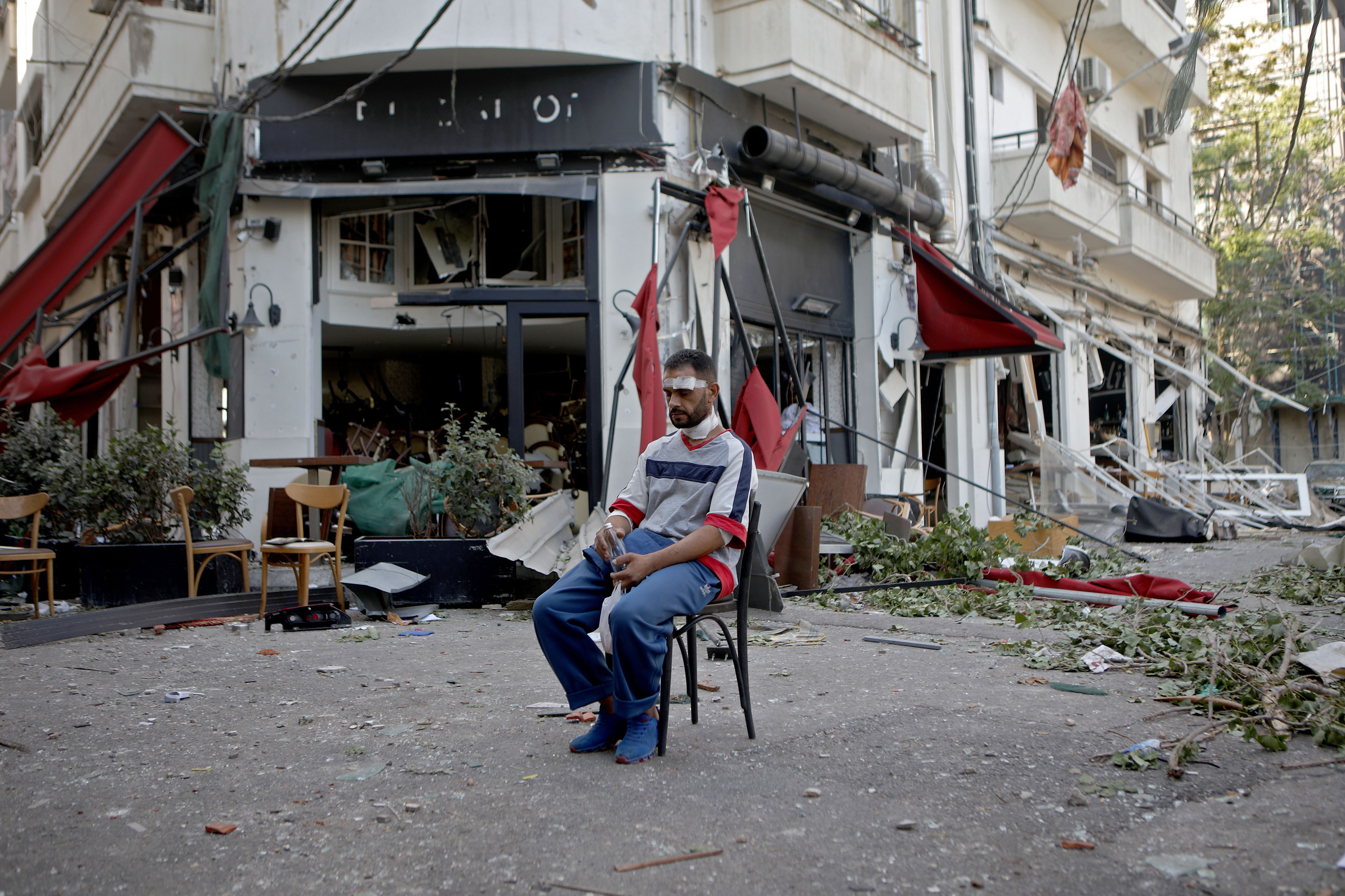 An injured person sits by a restaurant on August 5.