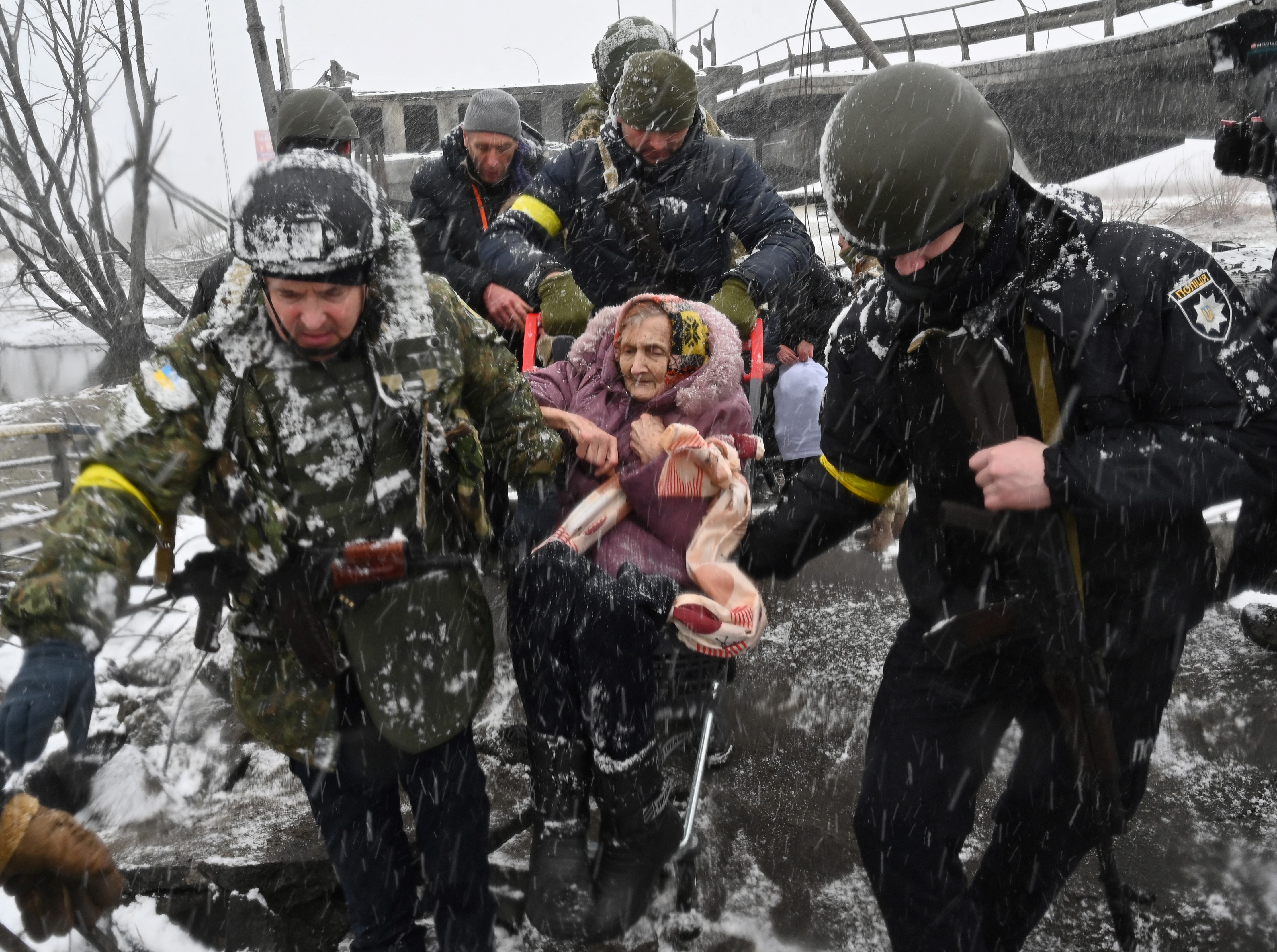Ukrainian soldiers help an elderly woman to cross a destroyed bridge as she evacuates the city of Irpin, northwest of Kyiv, on March 8.