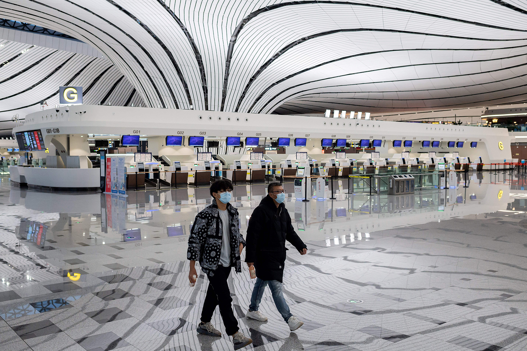 Two men walk through a nearly empty terminal at Daxing international airport in Beijing on Friday, February 14. 