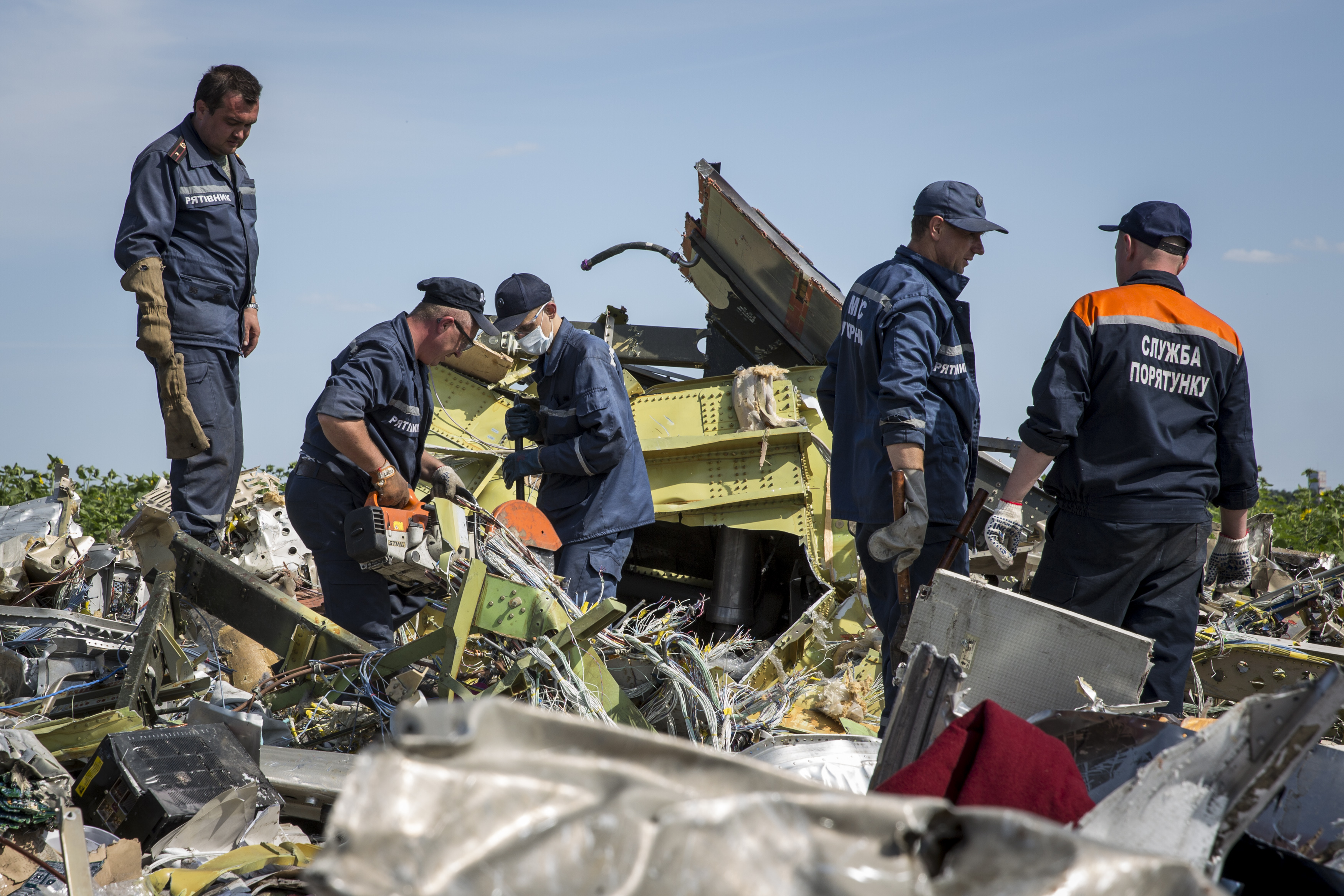 Ukrainian rescue servicemen inspect part of the wreckage of Malaysia Airlines flight MH17 on July 20, 2014, in Rassipnoye, Ukraine