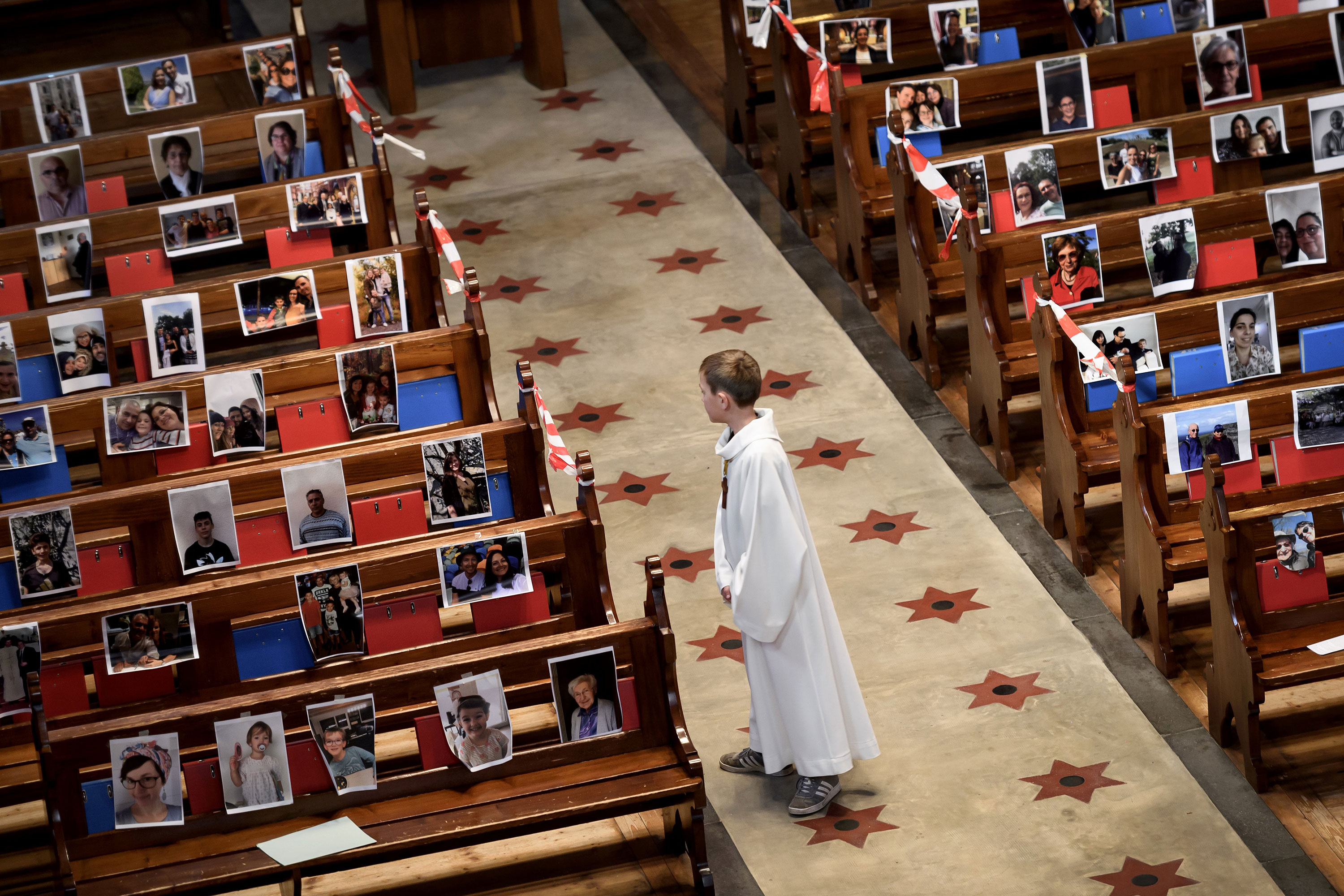 An altar boy stands in the central aisle of the Basilica of Neuchatel which pews display the portraits of 400 parishioners unable to attend the mass due to coronavirus on May 3.