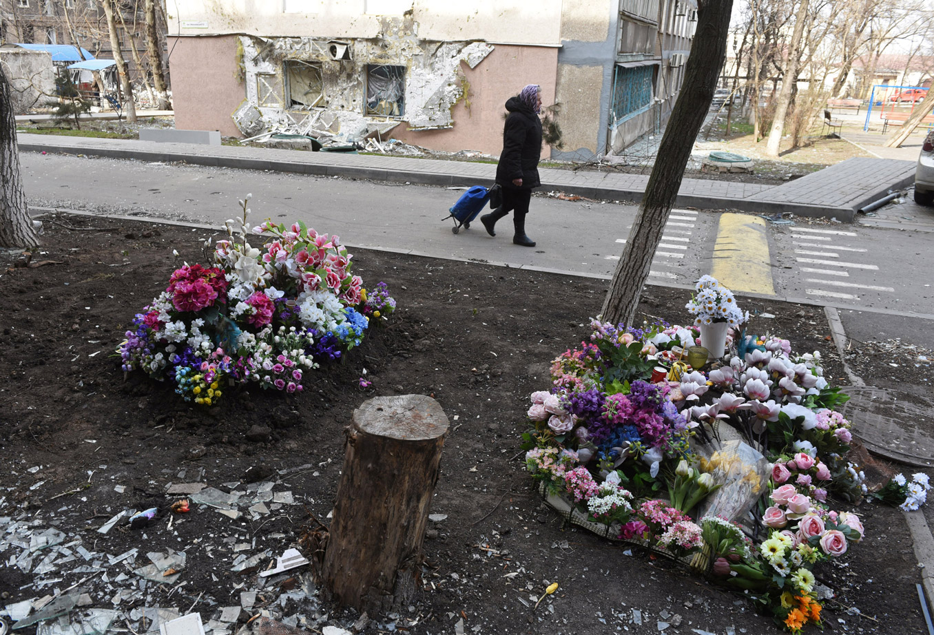 A woman walks past graves of local residents killed during the fighting in Mariupol, on April 3.