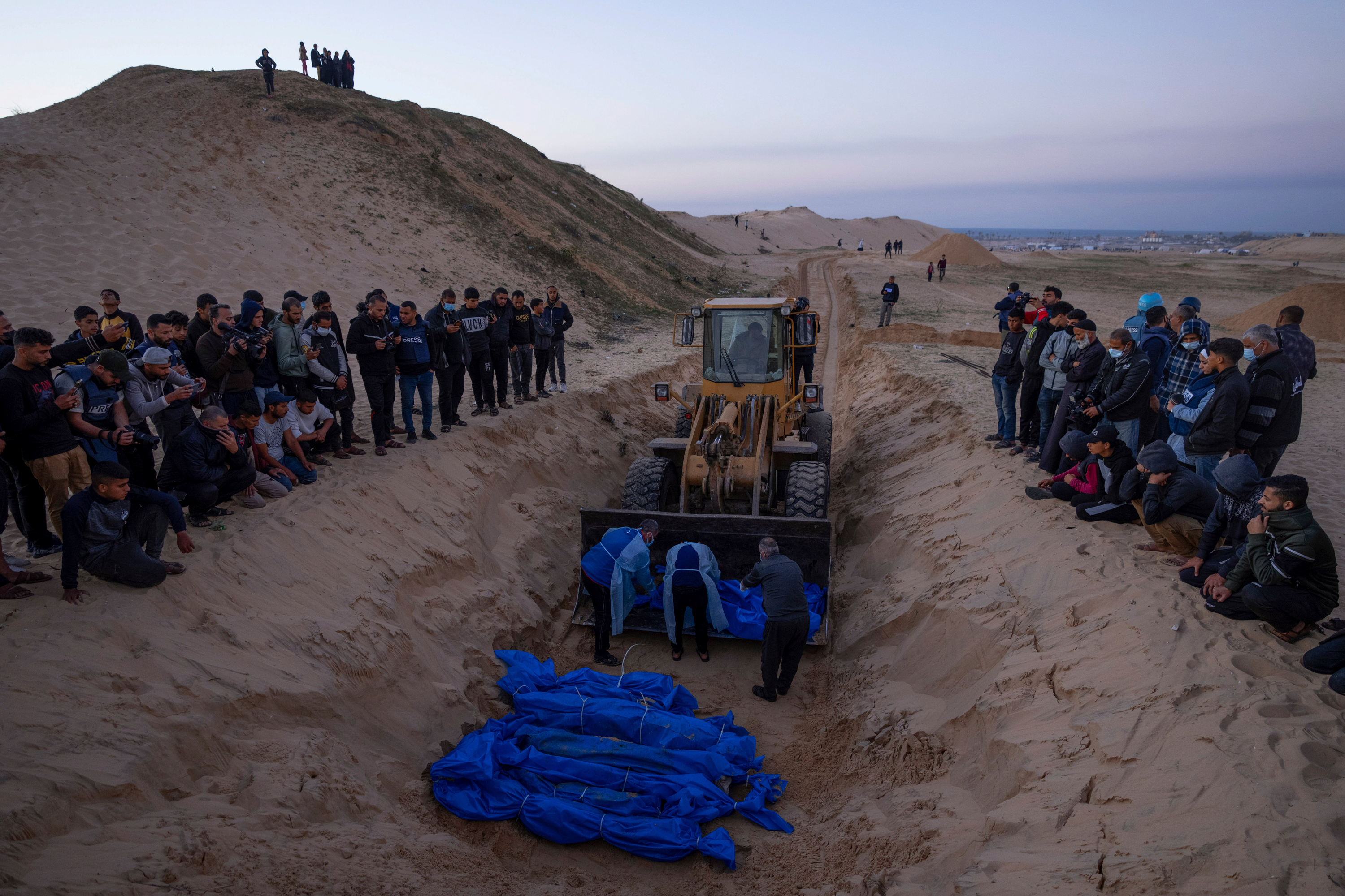 A bulldozer unloads the bodies of Palestinians killed in fighting with Israel and turned over by the Israeli military during a mass funeral in Rafah, Gaza, on December 26.