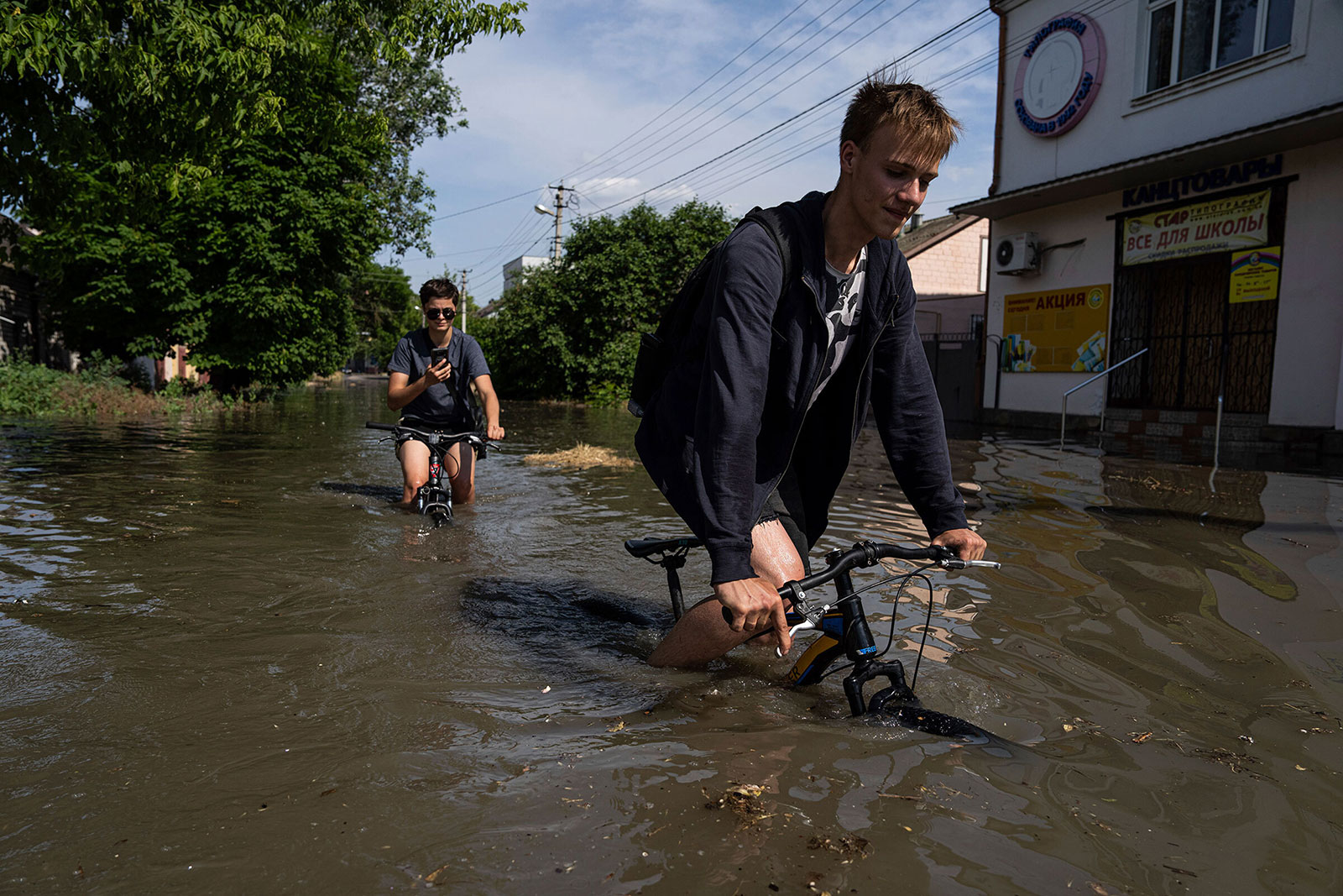 Residents ride bicycles along a flooded road in Kherson, Ukraine.