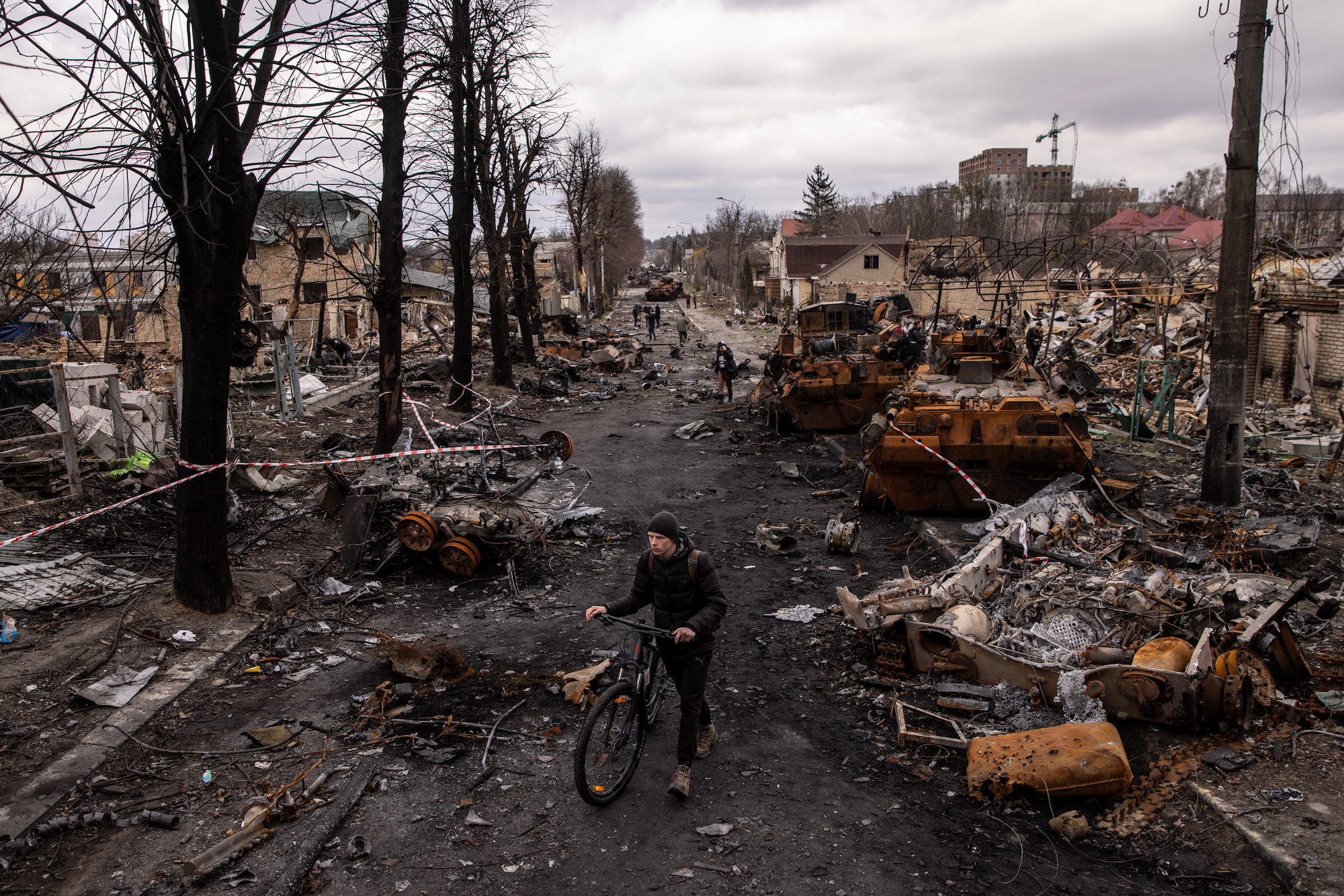  A man pushes his bike through debris and destroyed Russian military vehicles on April 06, 2022 in Bucha.