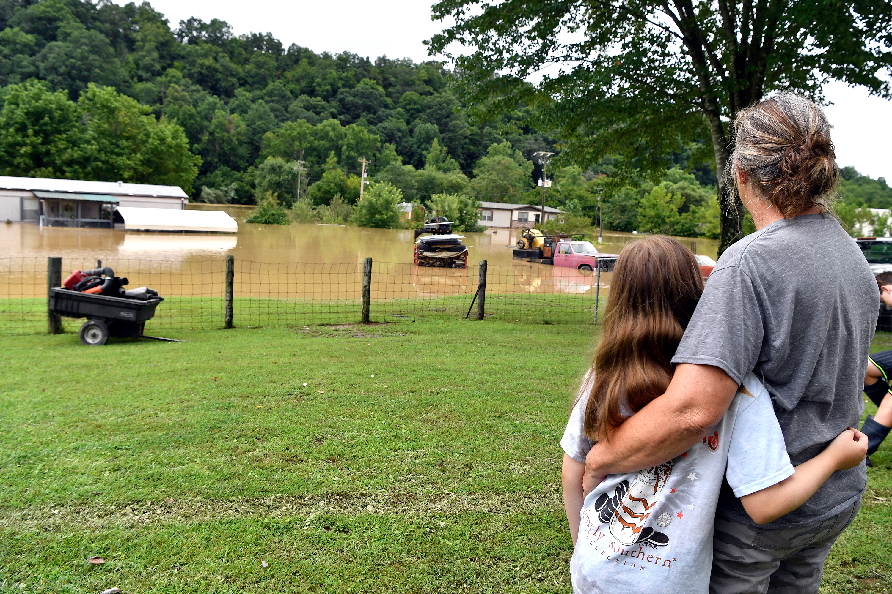 Bonnie Combs hugs her granddaughter Adelynn Bowling as they watch her property become submerged on July 28 in Jackson, Kentucky. 