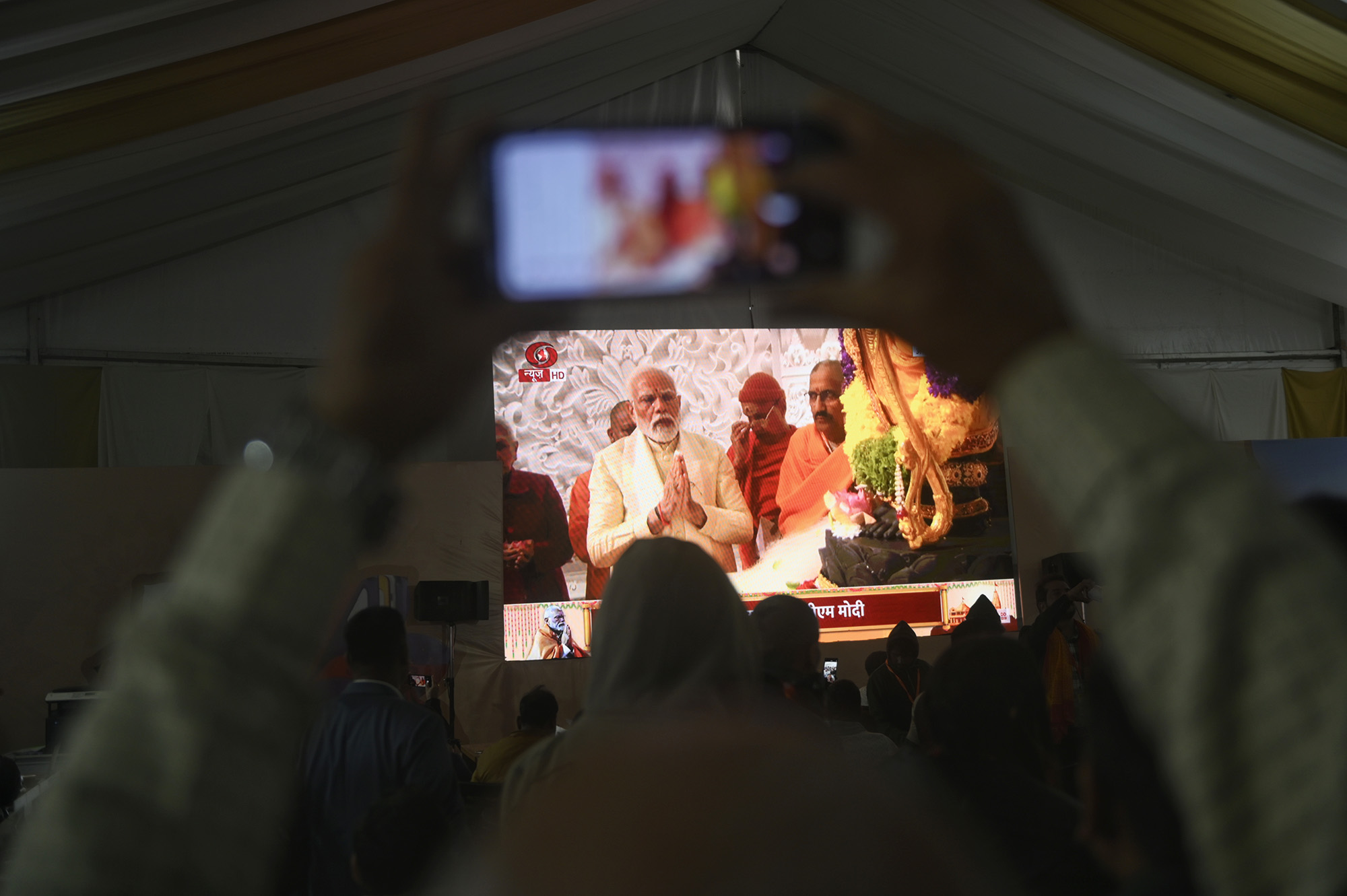 People watching the Ram temple consecration ceremony by Prime Minister of India, Narendra Modi, on a live streaming screen in a media center in Ayodhya, India, on January 22.