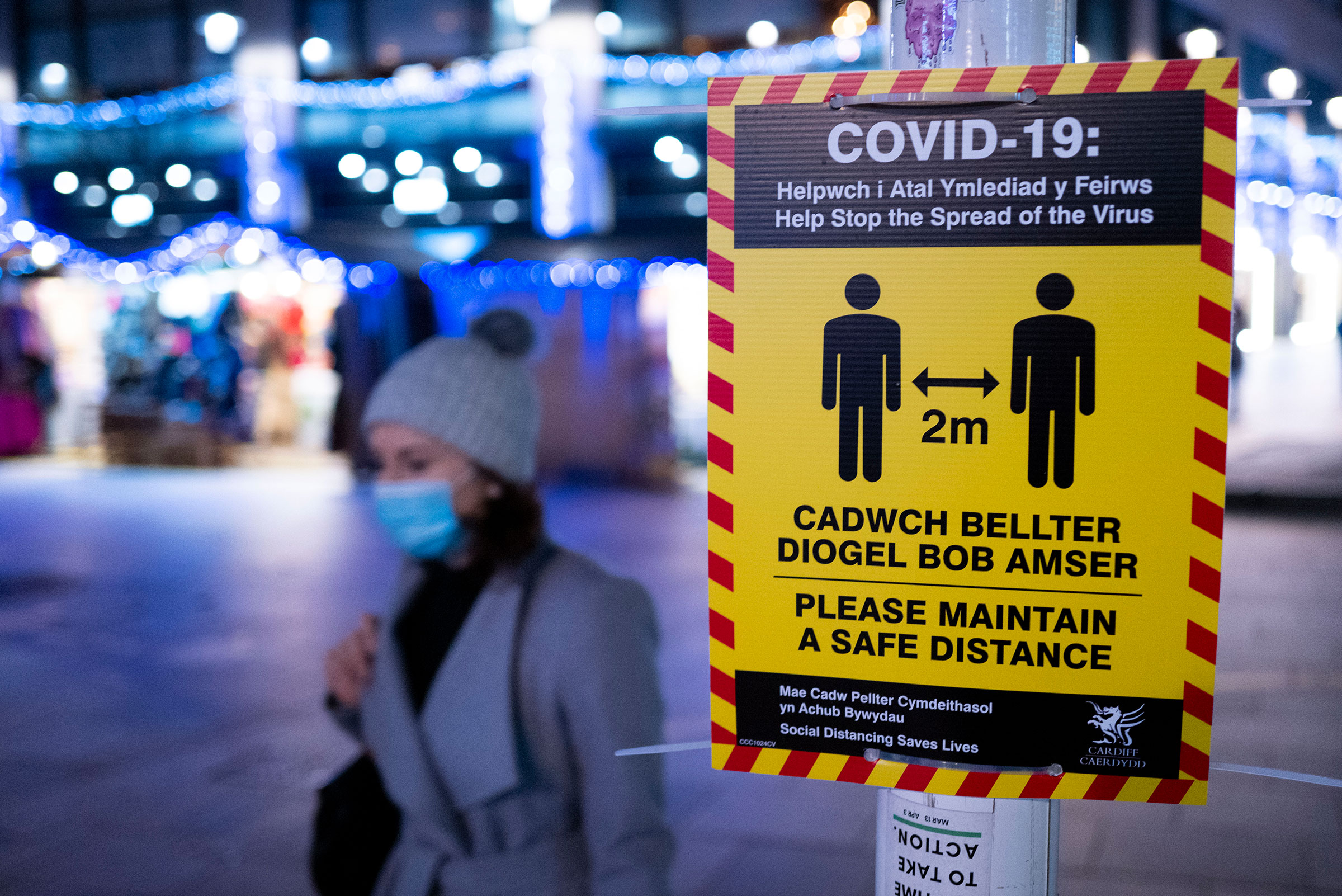 A woman walks past a sign showing Covid-19 precautions on December 14 in Cardiff, Wales. 