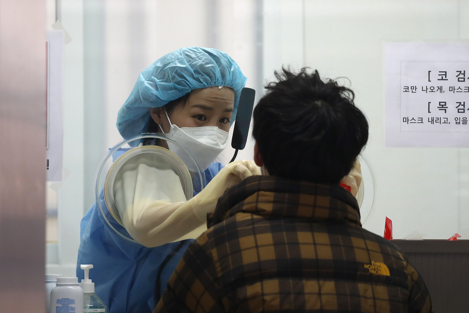 A medical professional take samples from people at a preliminary testing center in Seoul, South Korea, on December 12.