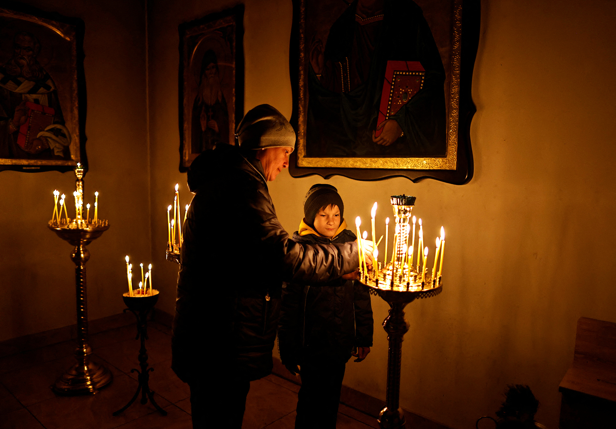 A woman lights a candle during Palm Sunday mass at a church in Bucha, Ukraine. 