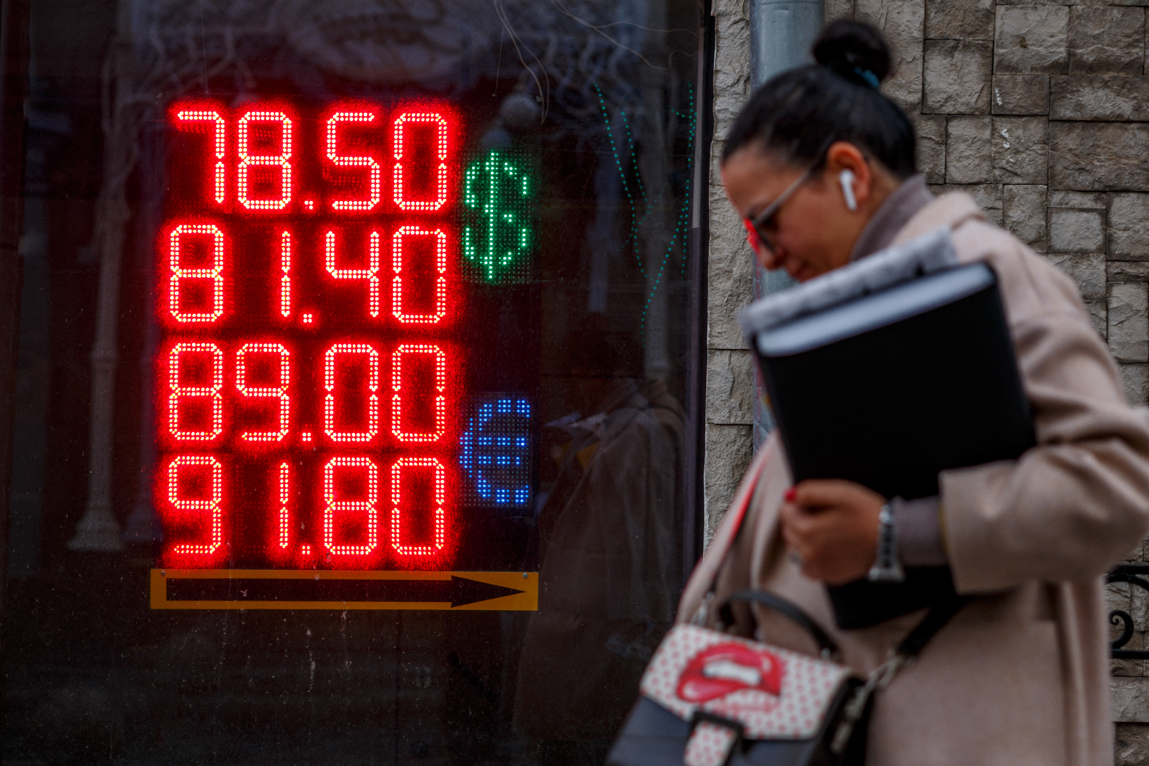 A woman walks past a board showing currency exchange rates of the US dollar and the euro against the Russian ruble in Moscow, Russia, on February 22.