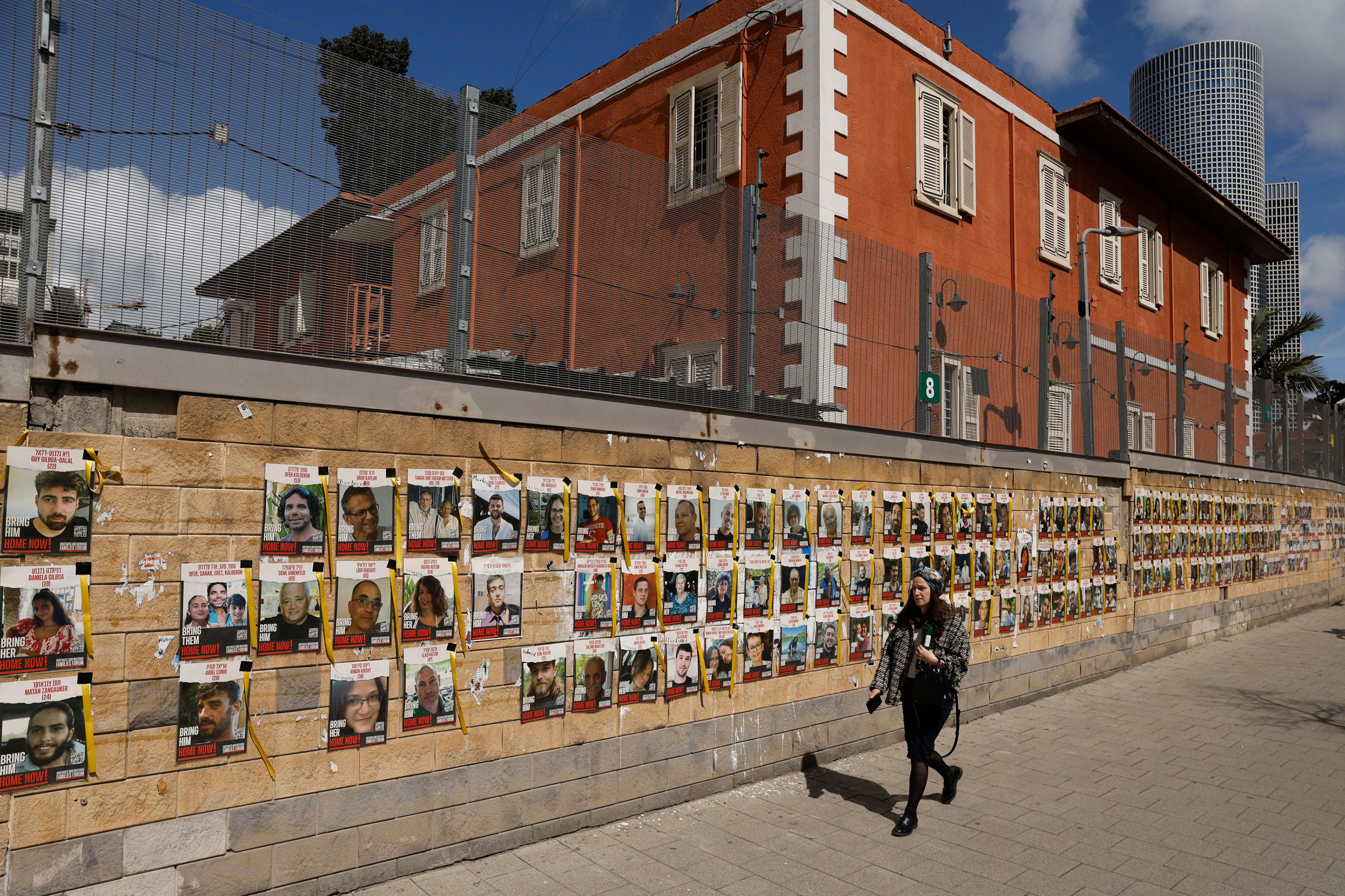 A person walks past a wall of pictures in Tel Aviv on March 7 which show hostages kidnapped by Hamas on October 7.